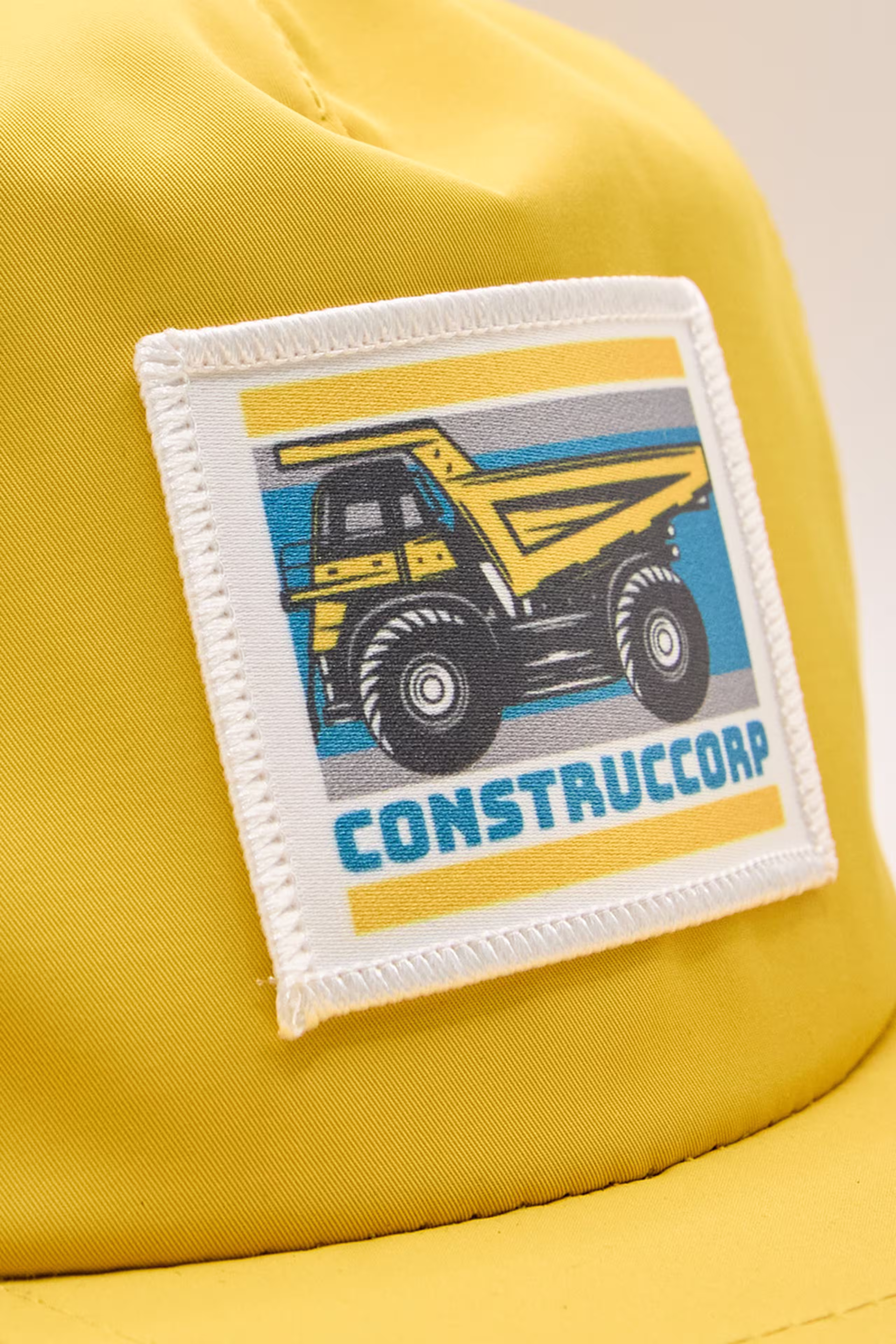 a sublimated patch with a dump truck illustration on a yellow hat