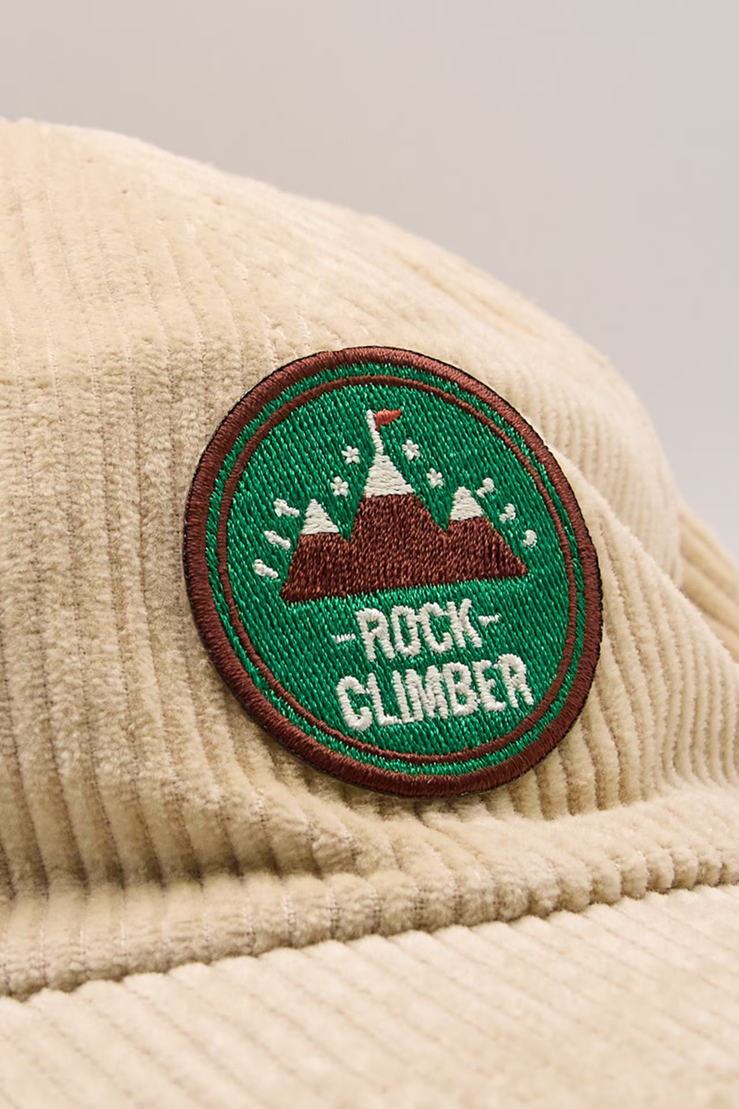 a circle, a green and brown embroidered patch of mountain, and the words rock climber