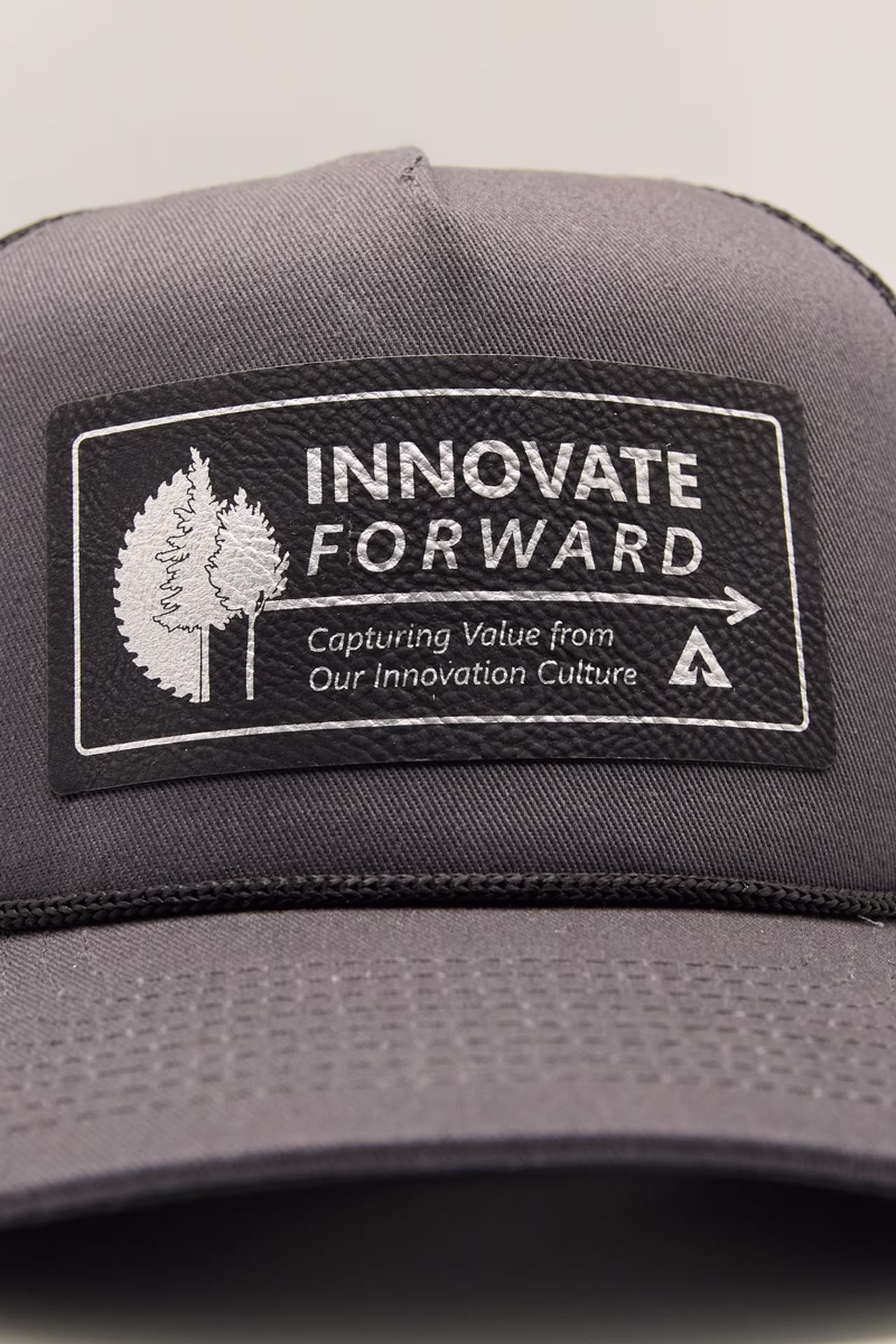 a black patch with siliver artwork on a grey and black trucker hat