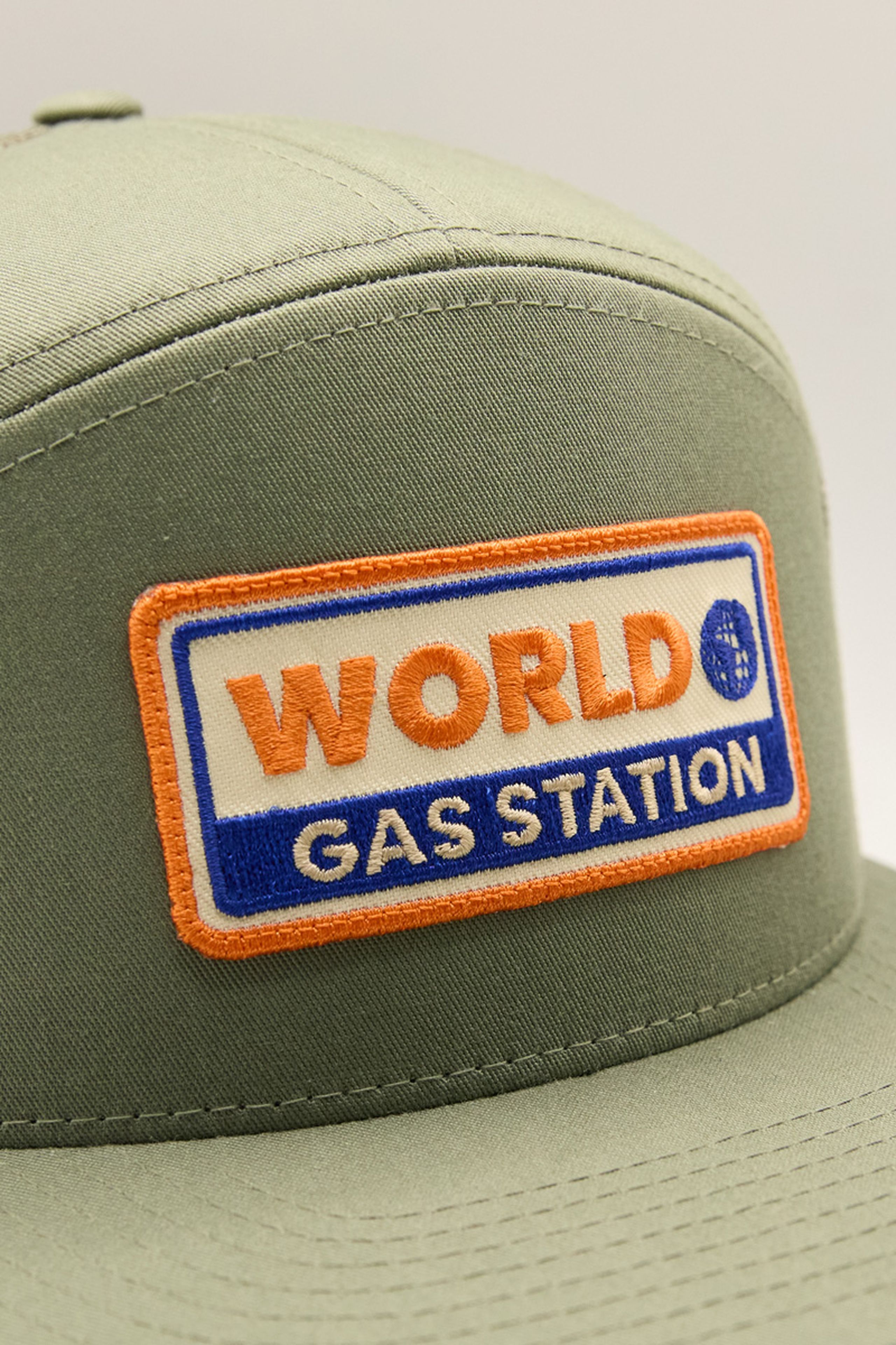a green hat with an orange, blue, and white rectangle embroidery patch