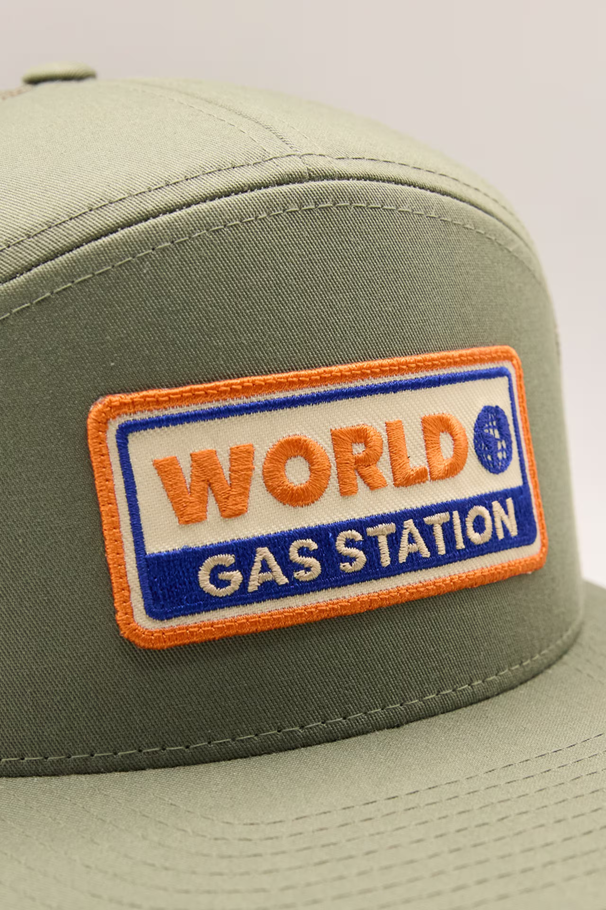 a green hat with an orange, blue, and white rectangle embroidery patch