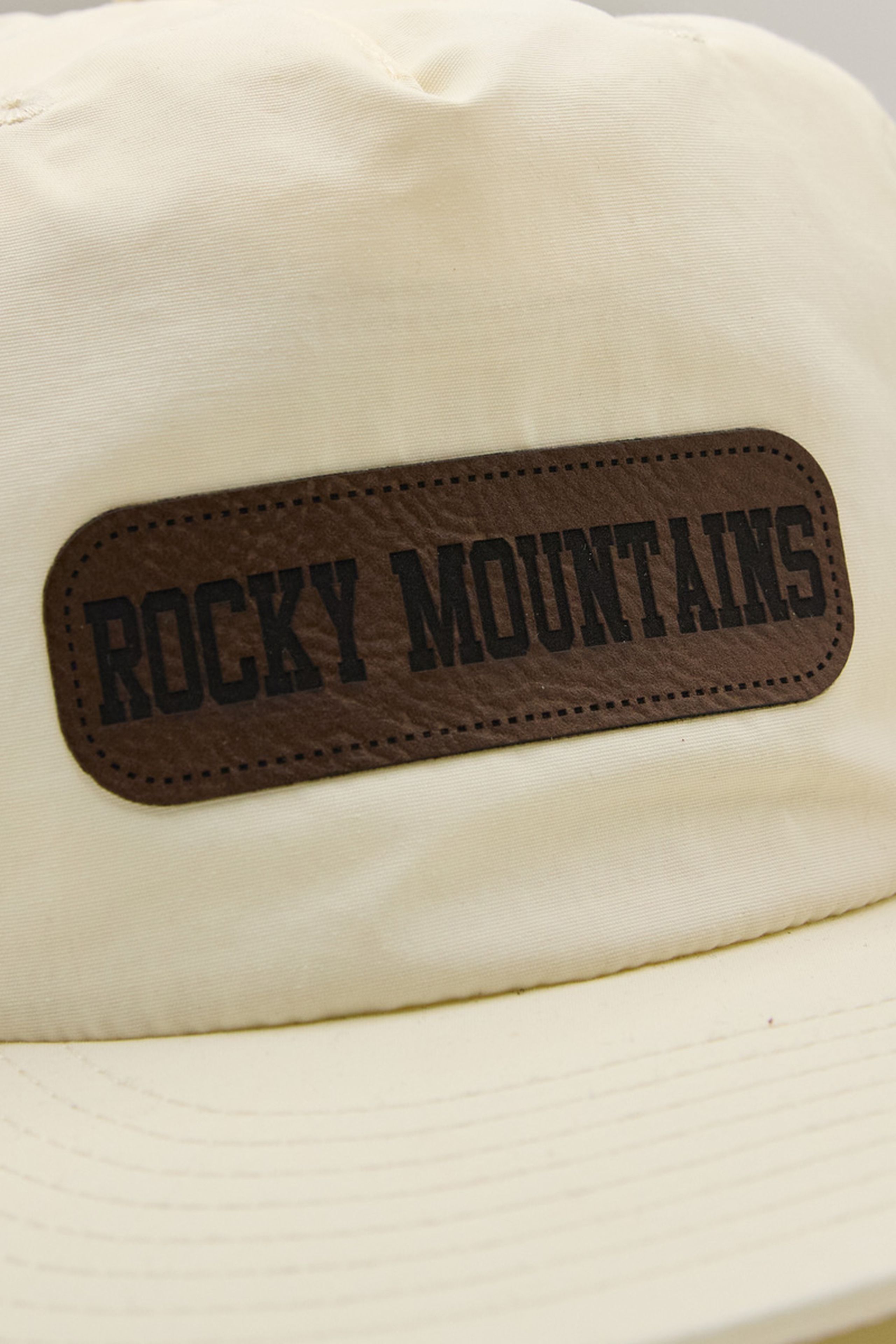 rounded corner rectangle faux leather patch on a cream-white hat