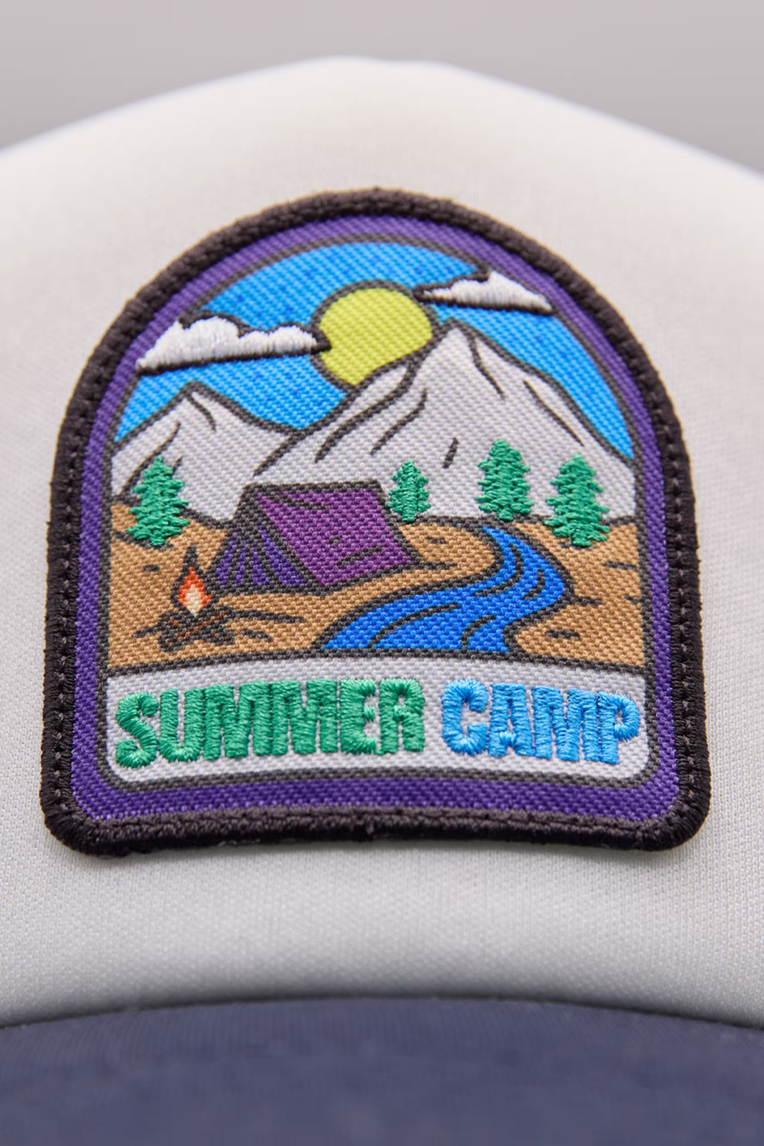 a print stitch patch of a tent along a river and mountains illustrations with Summer Camp in stitch.