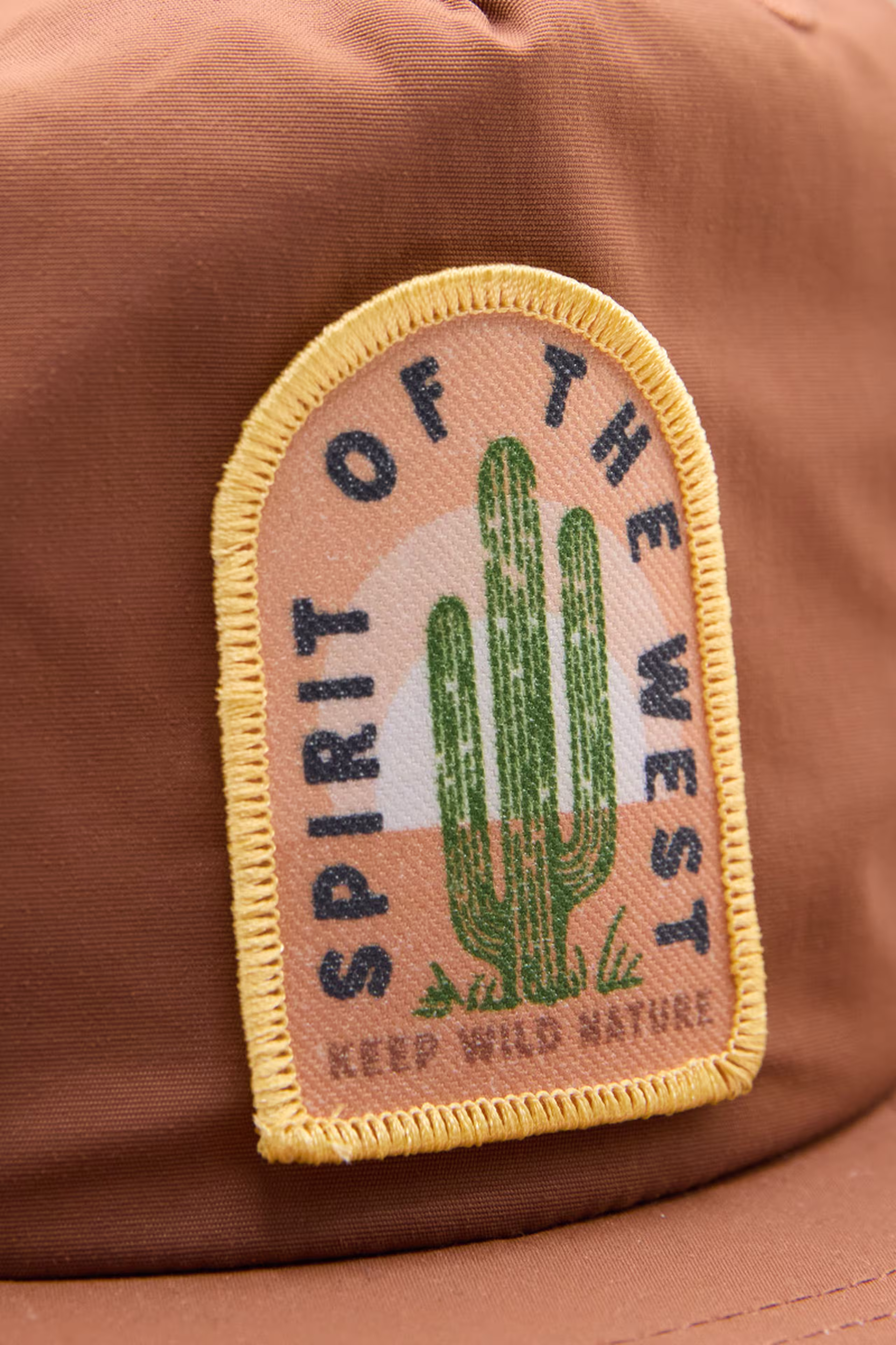 sublimated patch with an illustration of a cactus with the words spirit of the west on a brown hat