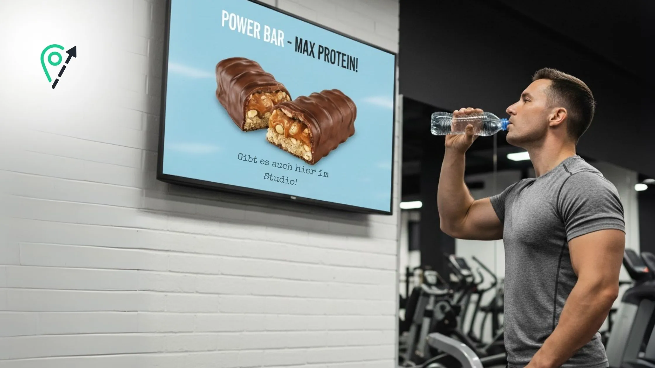 Ein Mann trinkt im Fitnessstudio ein Wasser, während er eine Anzeige für einen Power Bar auf einem Smart Screen betrachtet.