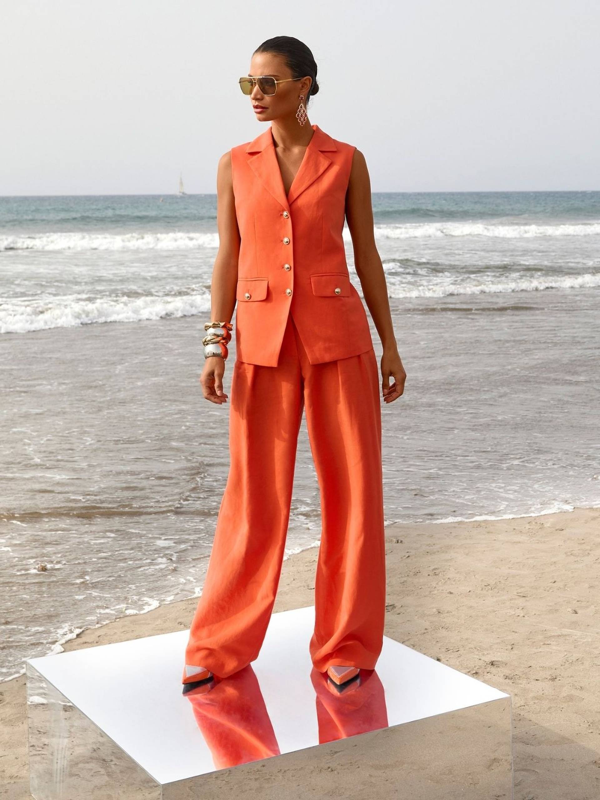 Oranger Zweiteiler mit weiter Hose und ärmelloser Weste, ein farbenfrohes Statement für moderne Hochzeitsgäste.