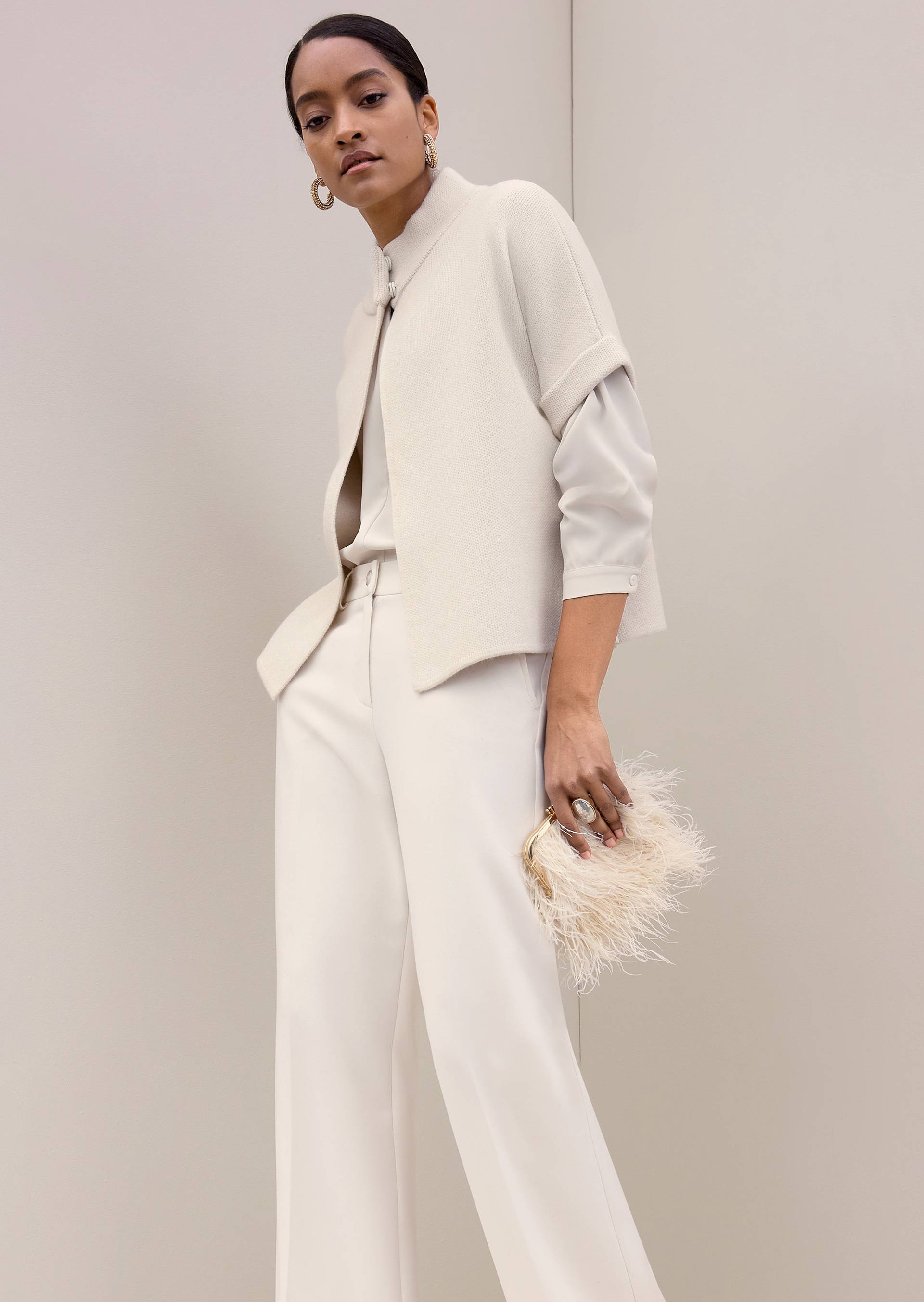 Overgangslook voor de herfst met witte cape-achtige vest, blouse en flanellen broek