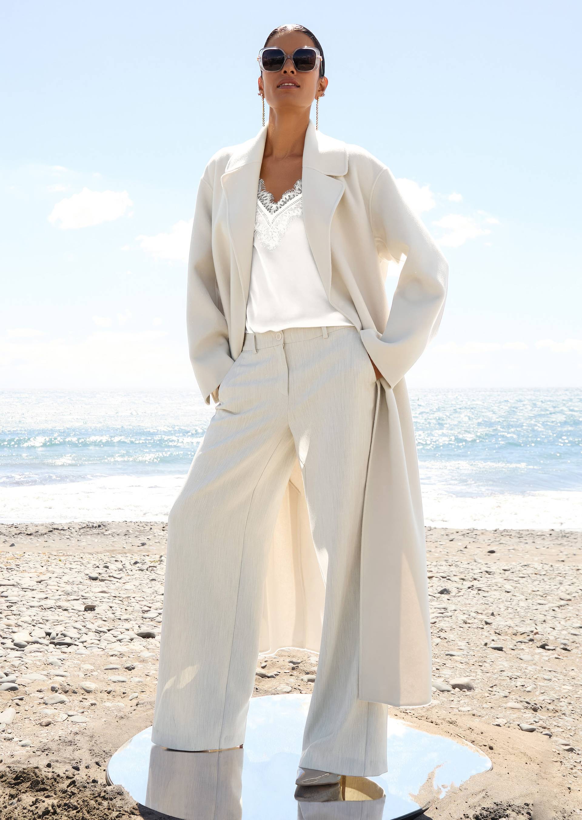 Winterlook in cremeweiß mit langem Wollmantel, weiter Hose und Spitzentop