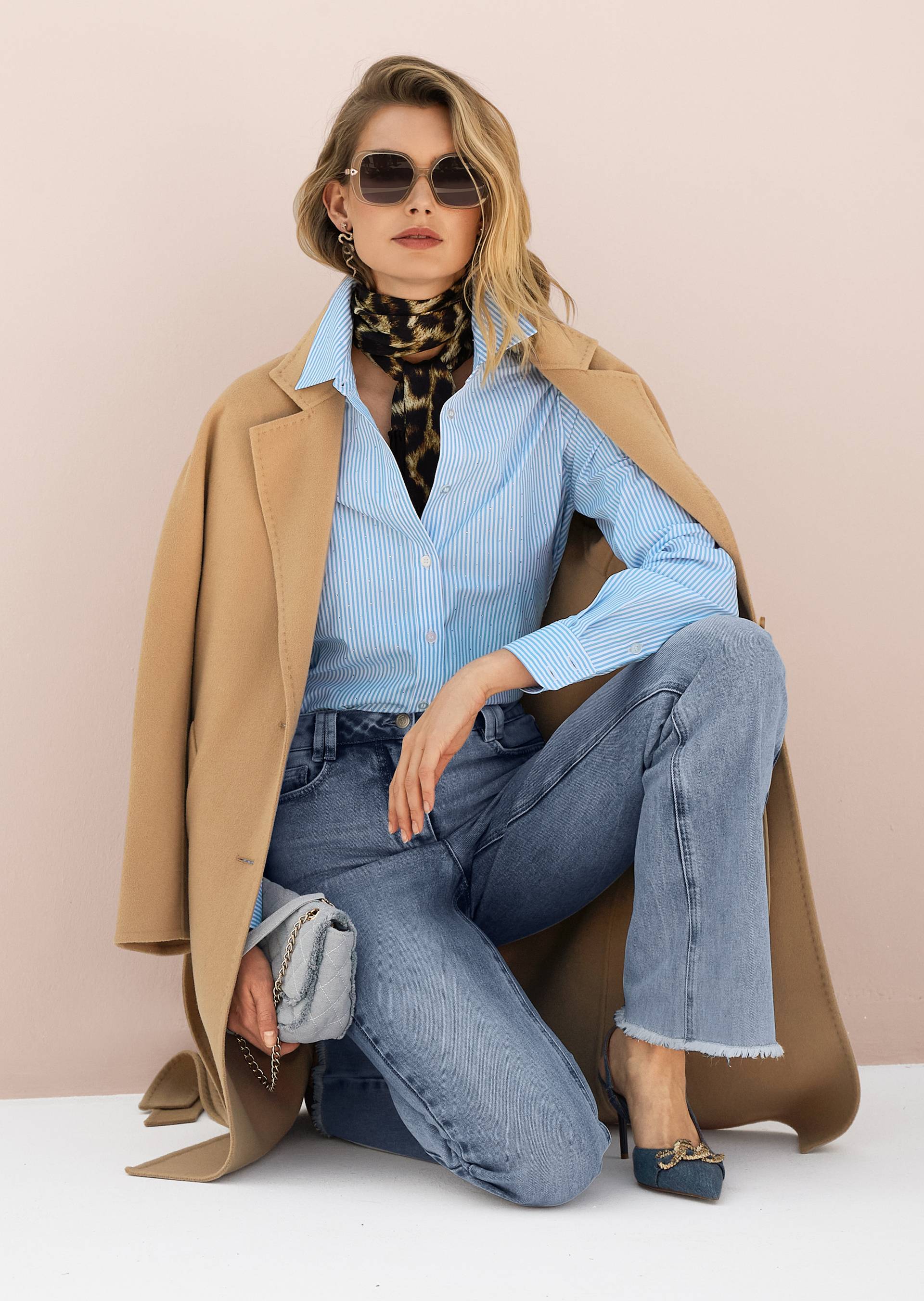 Fashionable style for women with jeans, blue striped blouse with rhinestones and beige coat.