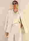 Woman wearing a light-coloured white corduroy suit and a satin top with lace