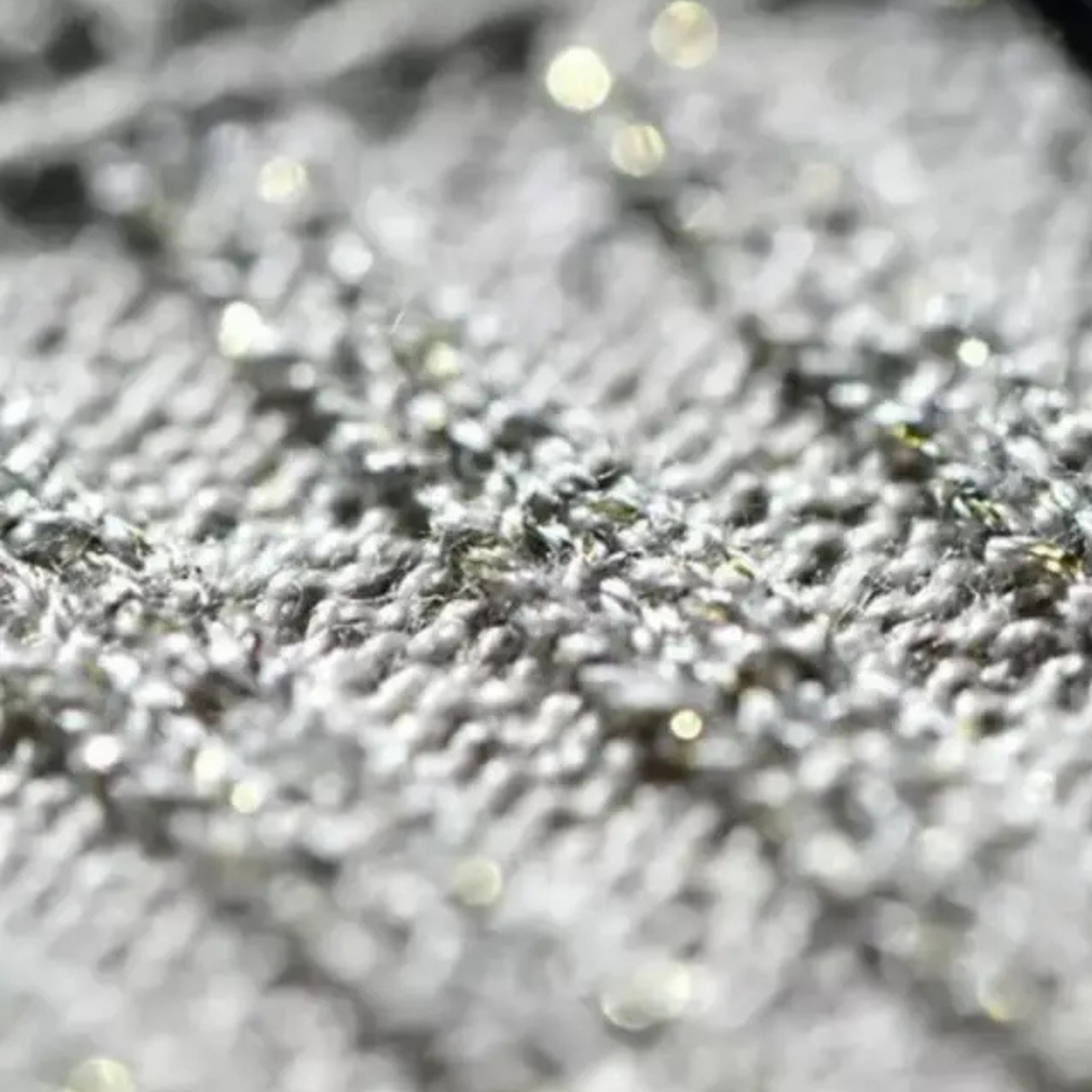 Metallisiertes Garn in Nahaufnahme mit feiner Strickstruktur und glänzenden Effekten