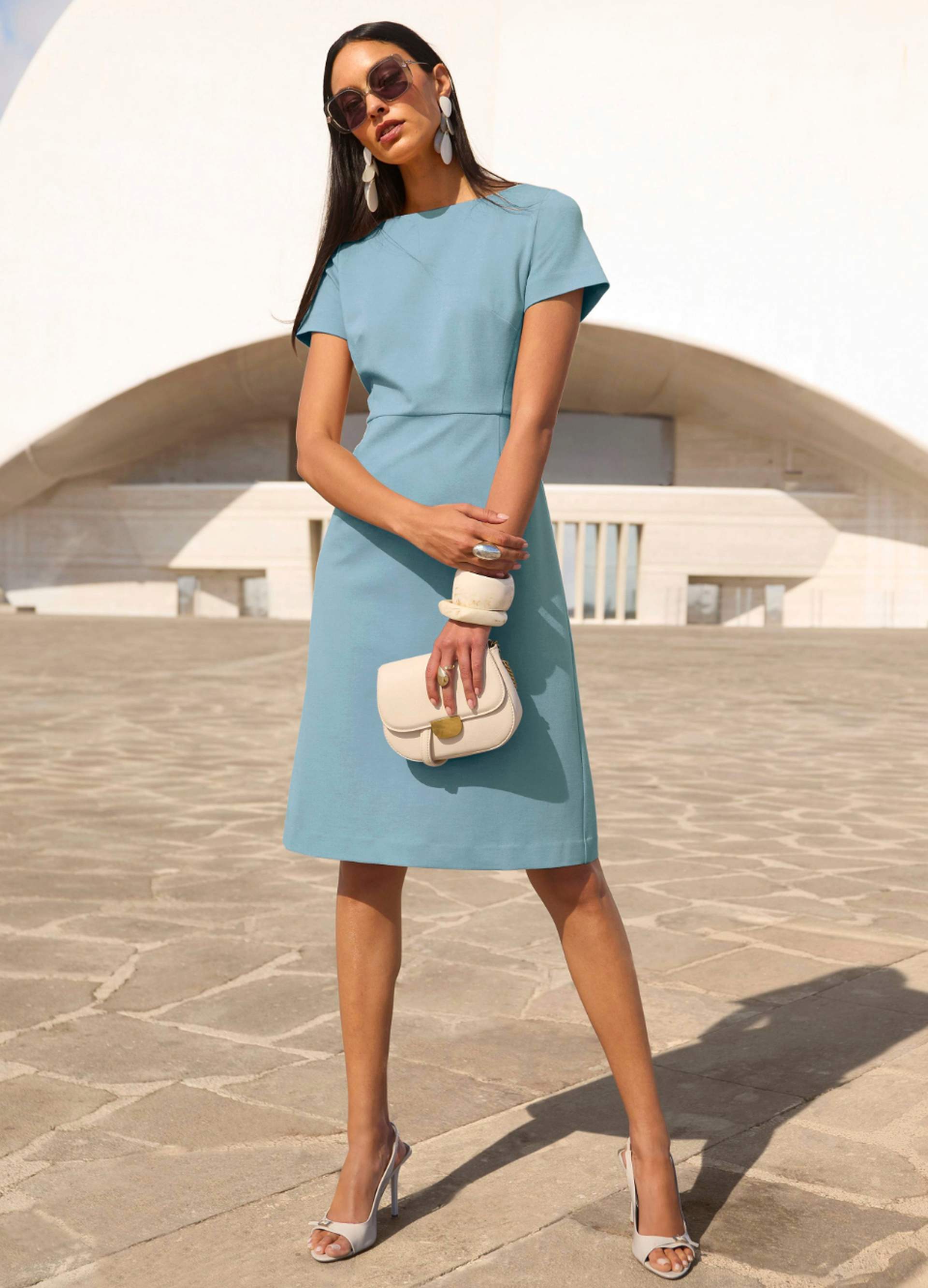 Damen-Businesskleid in moderner Midi-Länge, kombiniert mit Pumps und Tasche – professioneller Auftritt unterwegs.