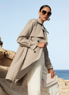 Beiger Trenchcoat mit Gürtel als French-Chic-Inspiration am Meer