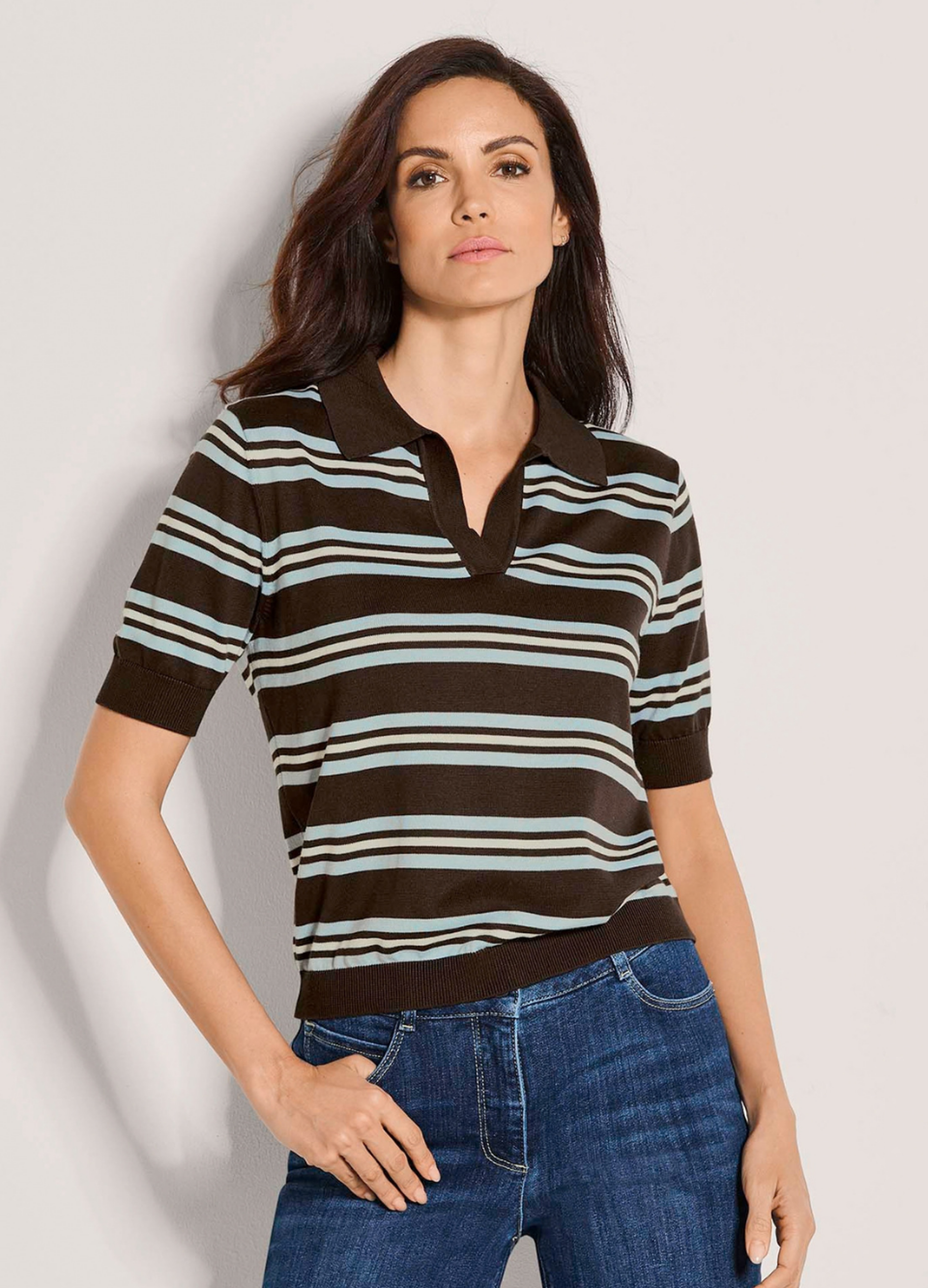 Frau in braunem Kurzarm-Strickpullover mit hellblauen und weißen Streifen und blauer Jeans