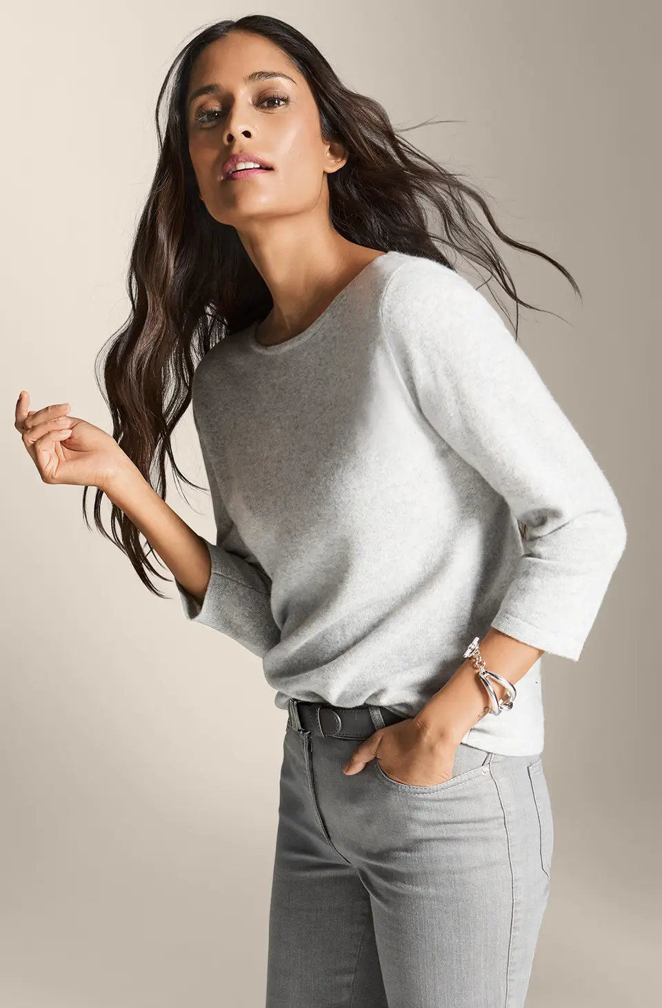 Pull en cachemire gris clair avec encolure ronde, manches trois-quarts et coupe droite, associé à un pantalon gris.