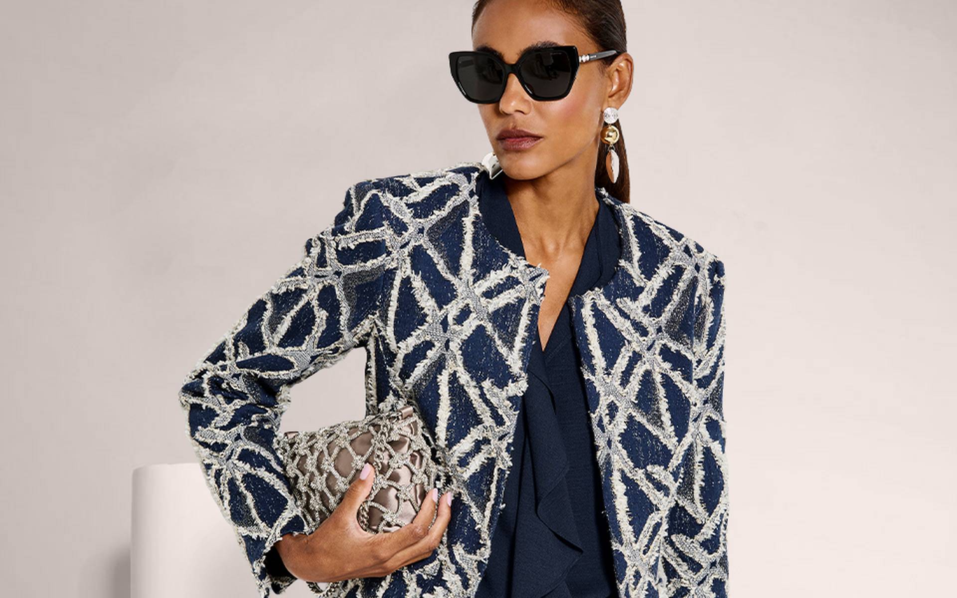 Navy cropped blazer with a white cloqué textured pattern, worn open over a top and straight-leg trousers.