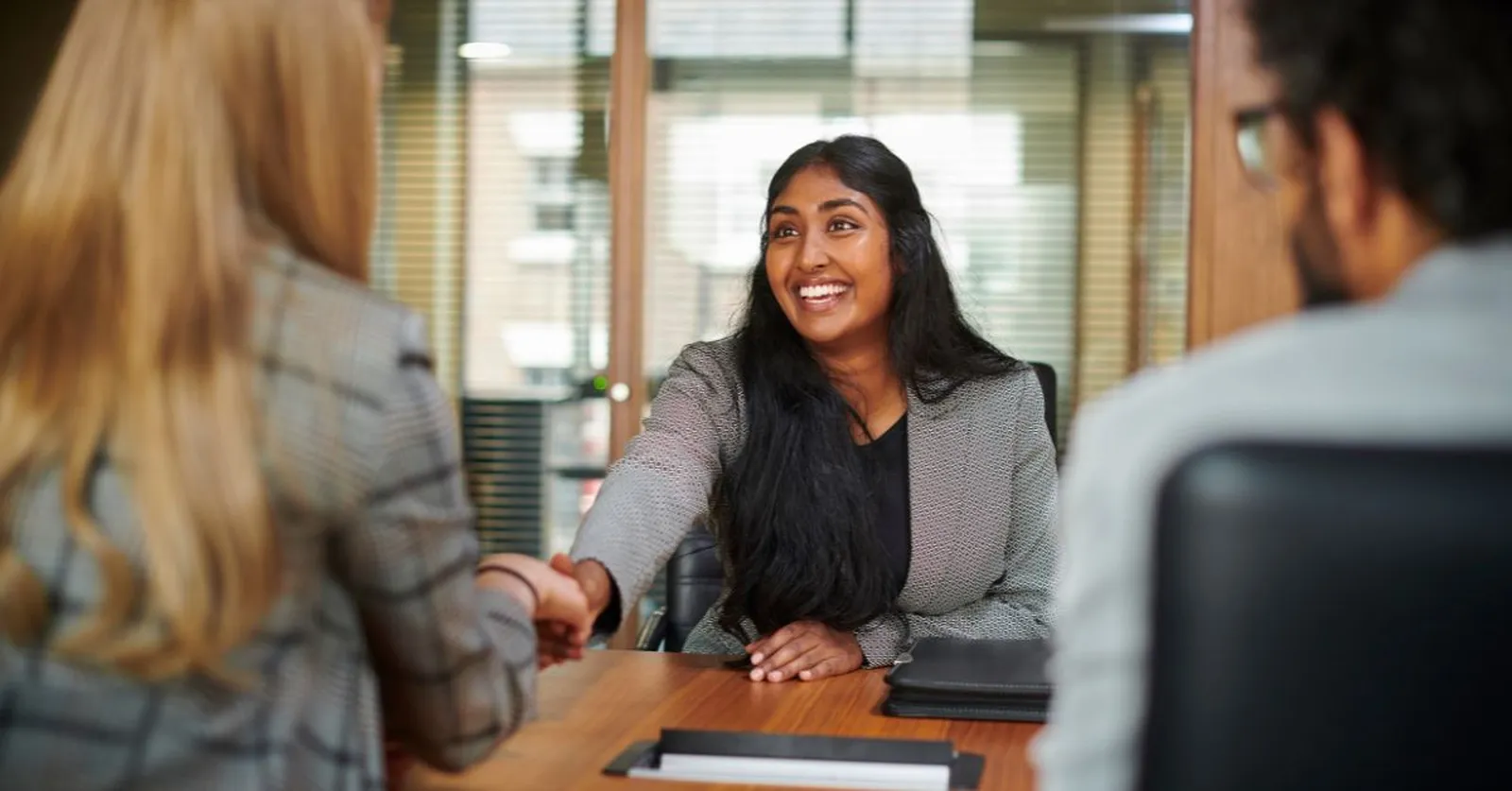 Woman being interviewed shaking hands with interviewer at AI Interview