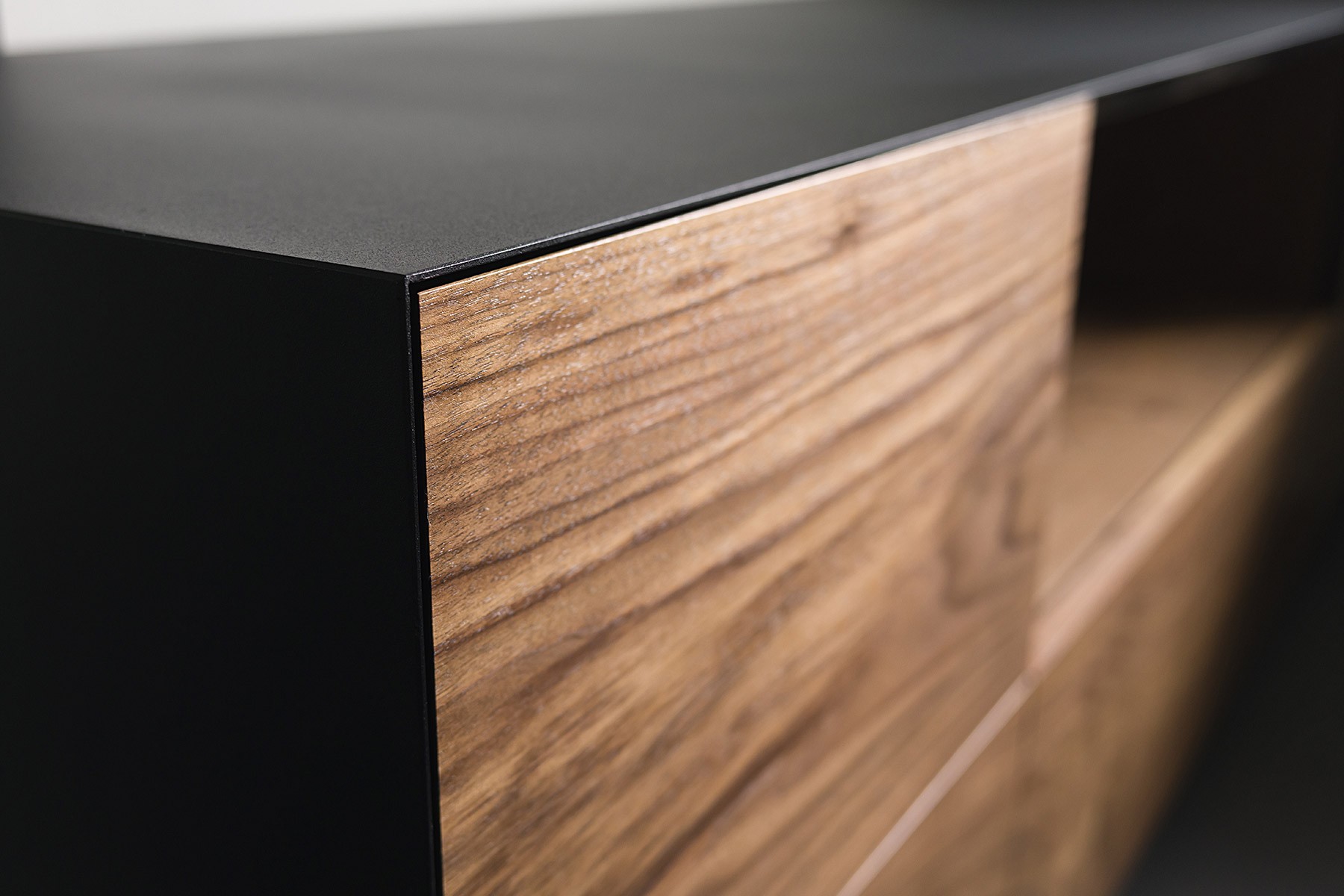 Close-up of a black and wooden cabinet with a black top and a wooden drawer on the right side.
