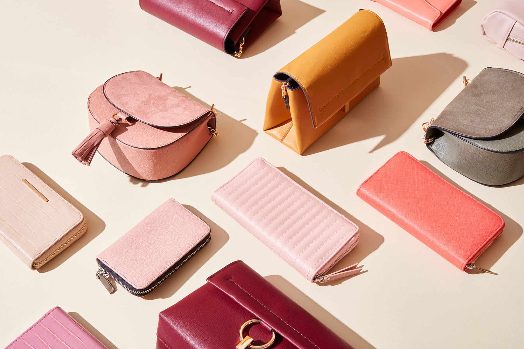 A collection of various colored leather handbags and wallets arranged on a white surface, showcasing different styles and designs.