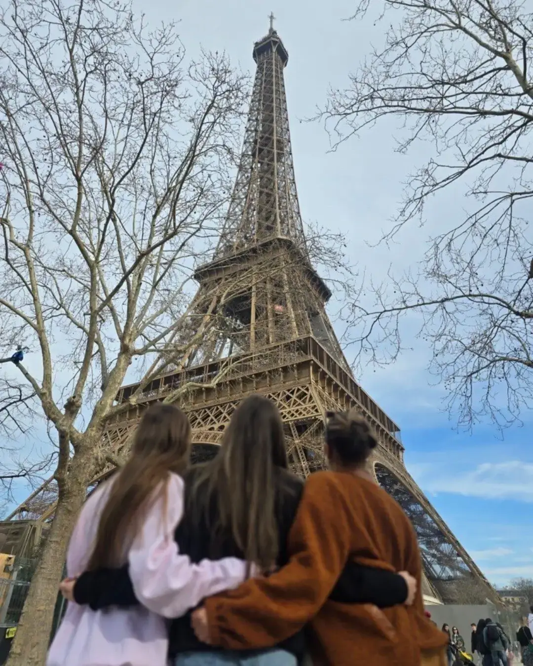 Three travelers looking at the Eiffel Tower in Paris, France