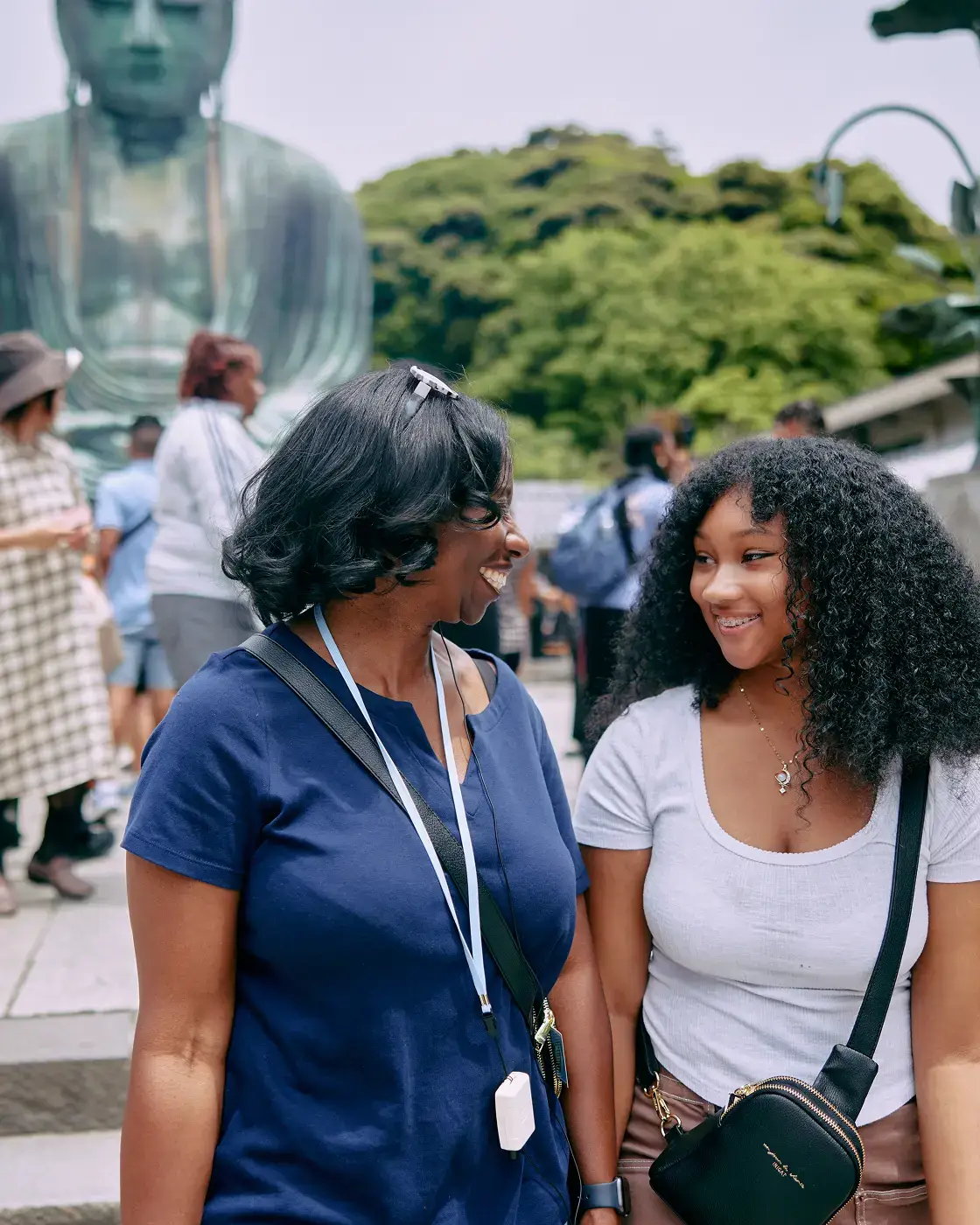 A mother and daughter smile at each other in front of Great Buddha