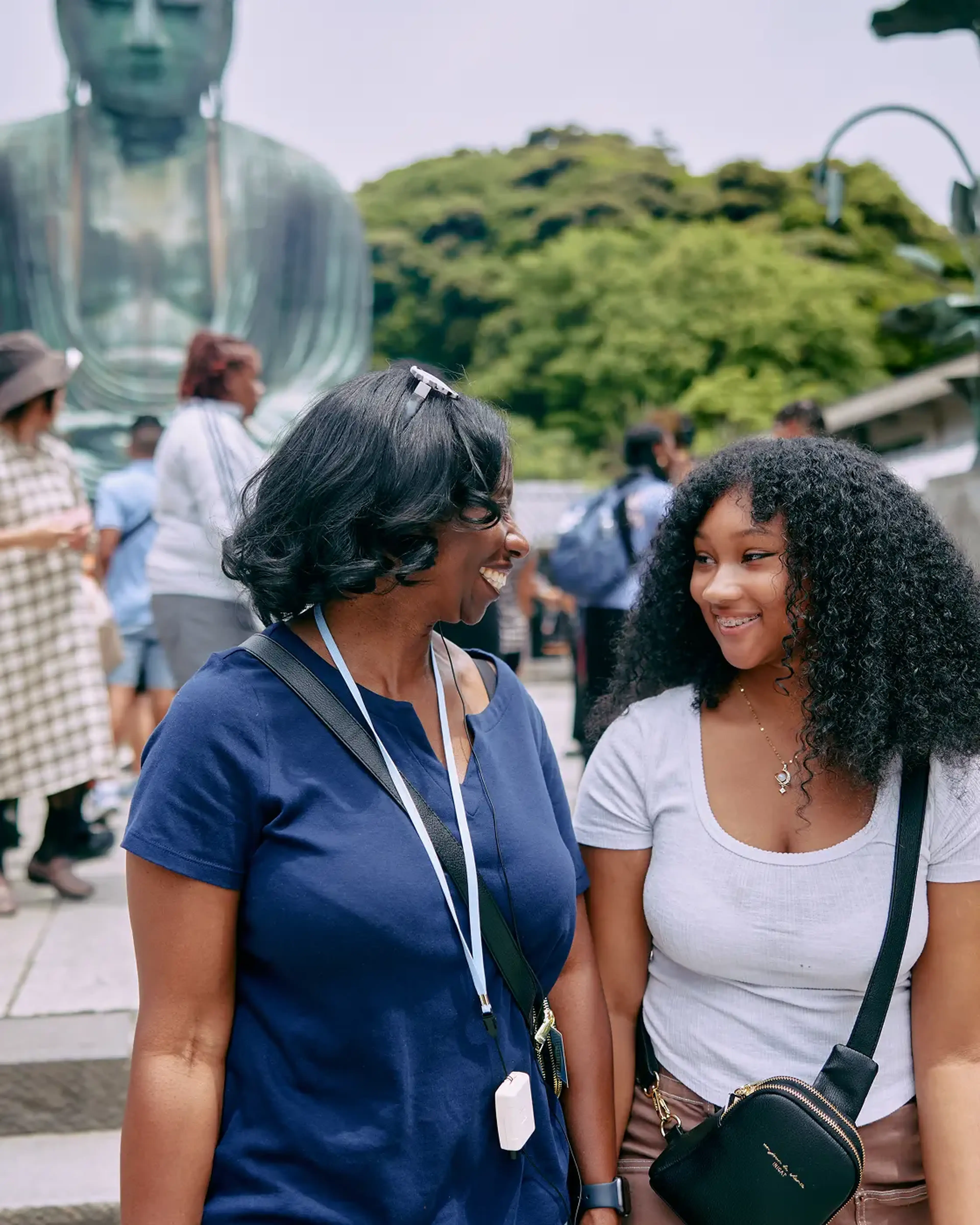 A mother and daughter smile at each other in front of Great Buddha
