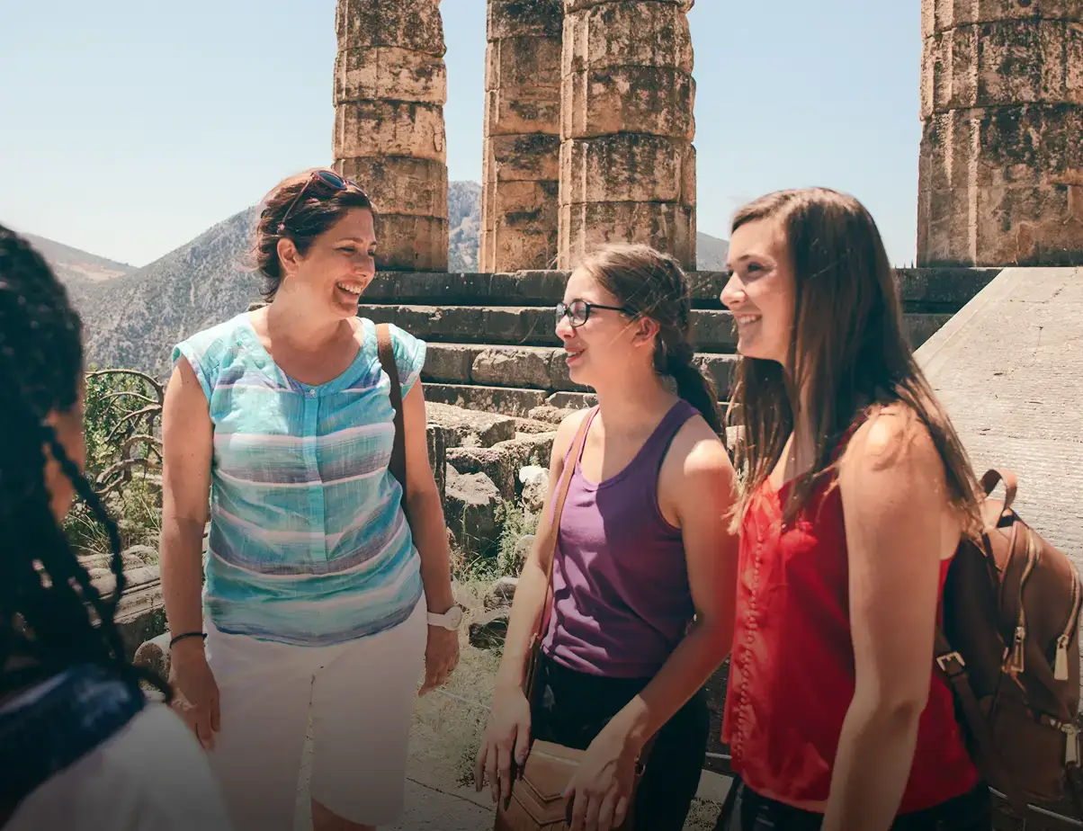 Group laughing together in front of ancient ruins at Delphi, Greece.