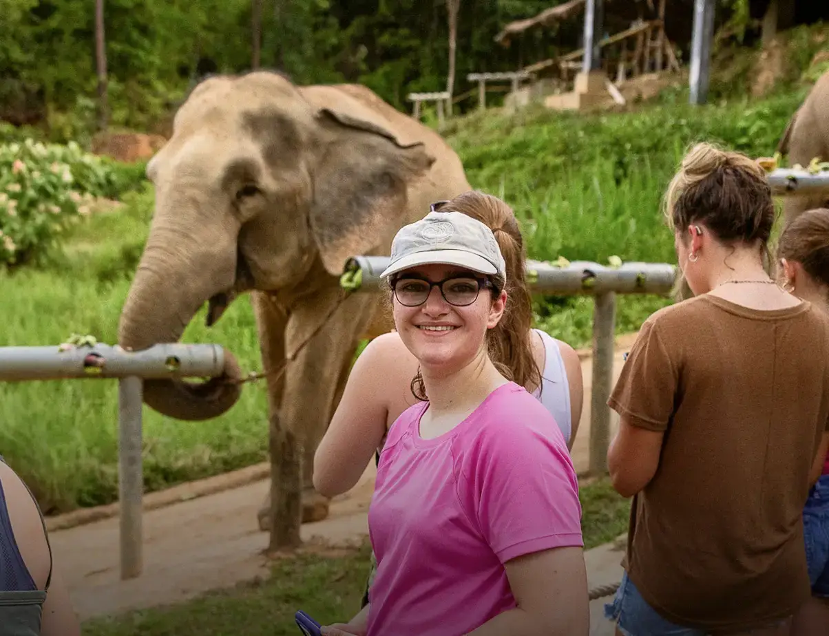 Student posing in front of elephant in Thailand