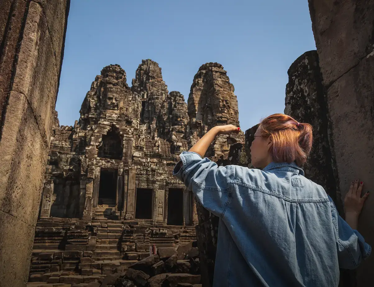 Traveler looking at the stone faces of Bayon Temple in Angkor Thom, Cambodia.