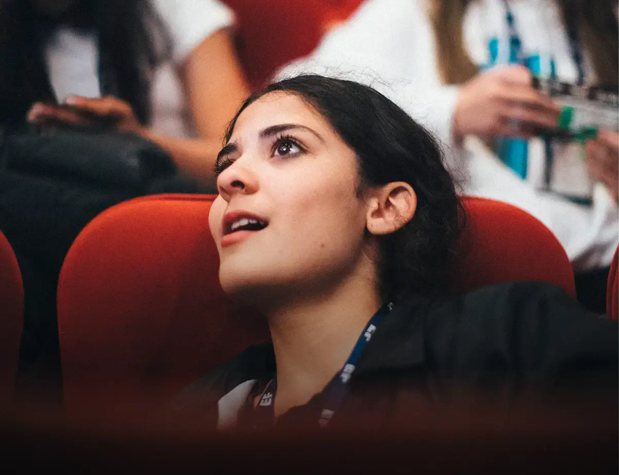 Student watching a theater performance with an amazed expression from a red seat.