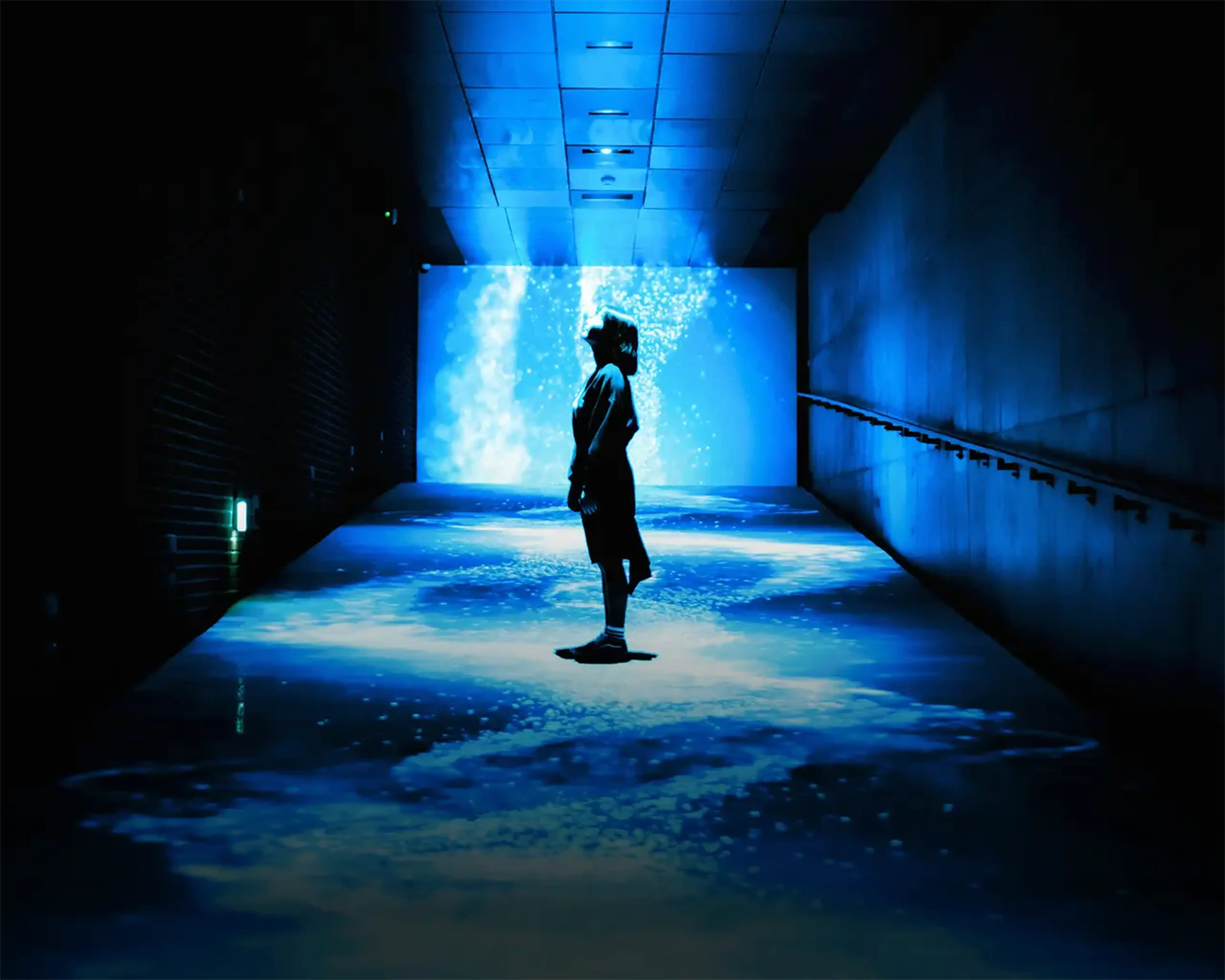 Student stands in a futuristic blue-lit exhibit in Seoul, South Korea.