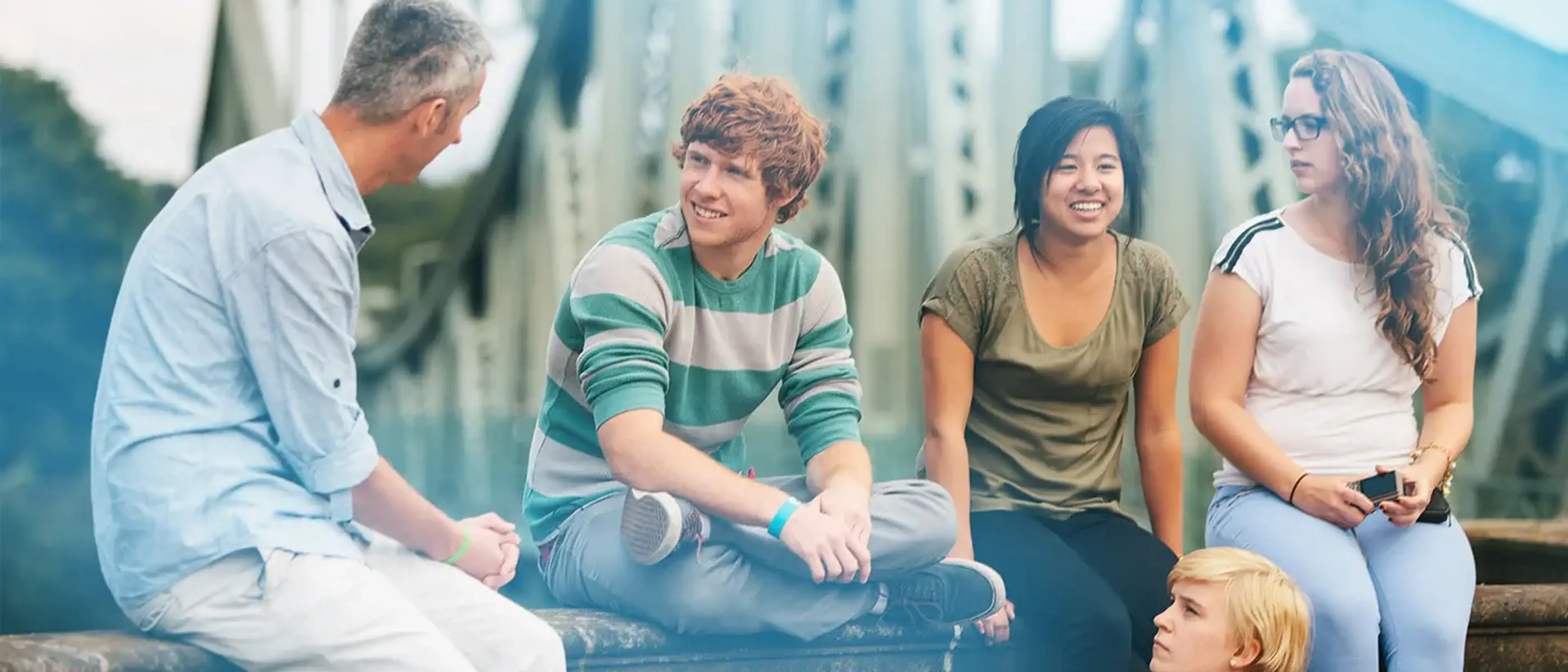 group of students sitting on a bridge