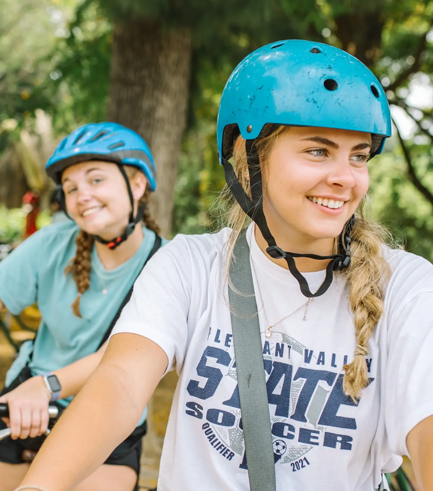 Two teen girls on bikes with helmets