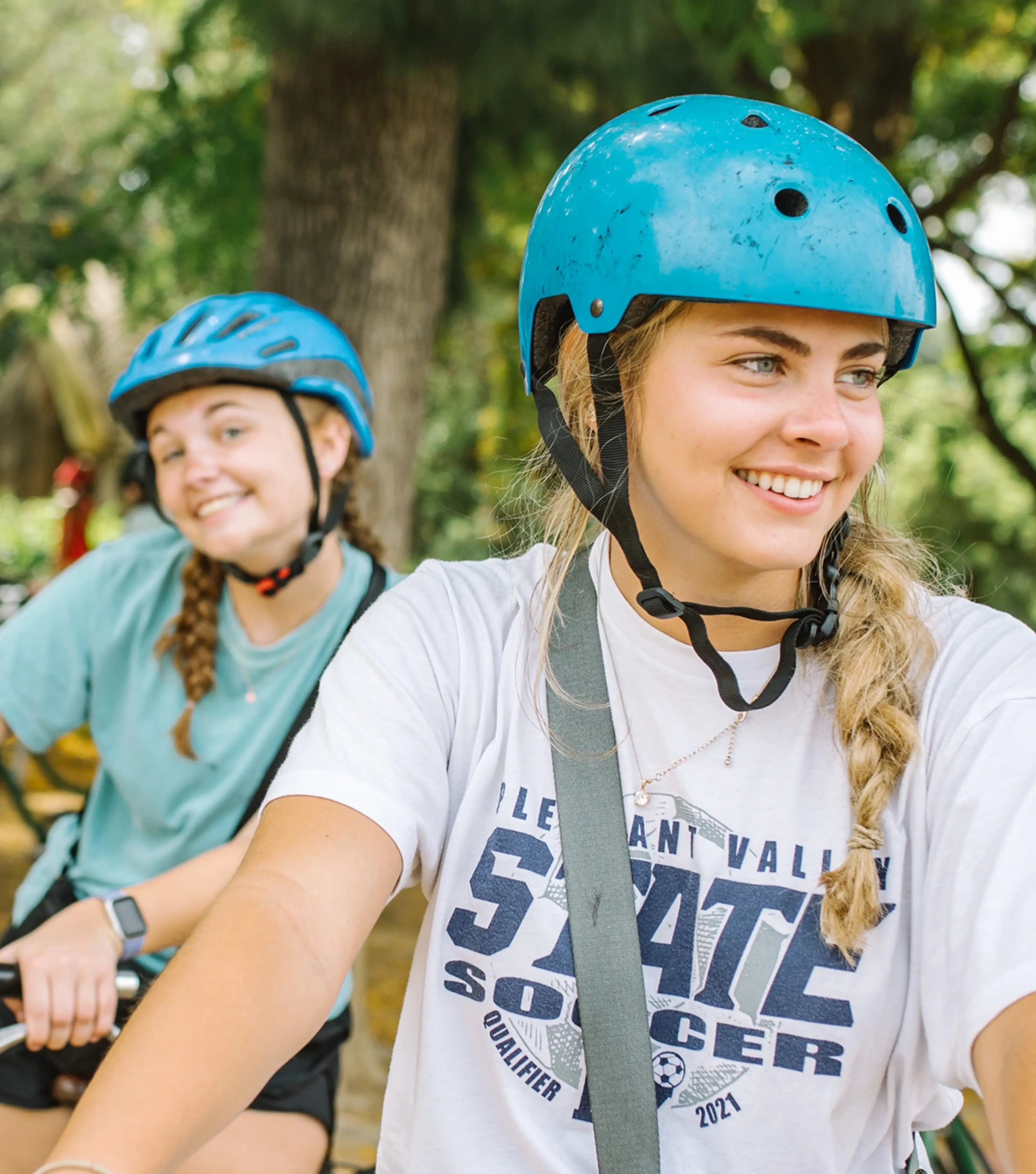 Two teen girls on bikes with helmets