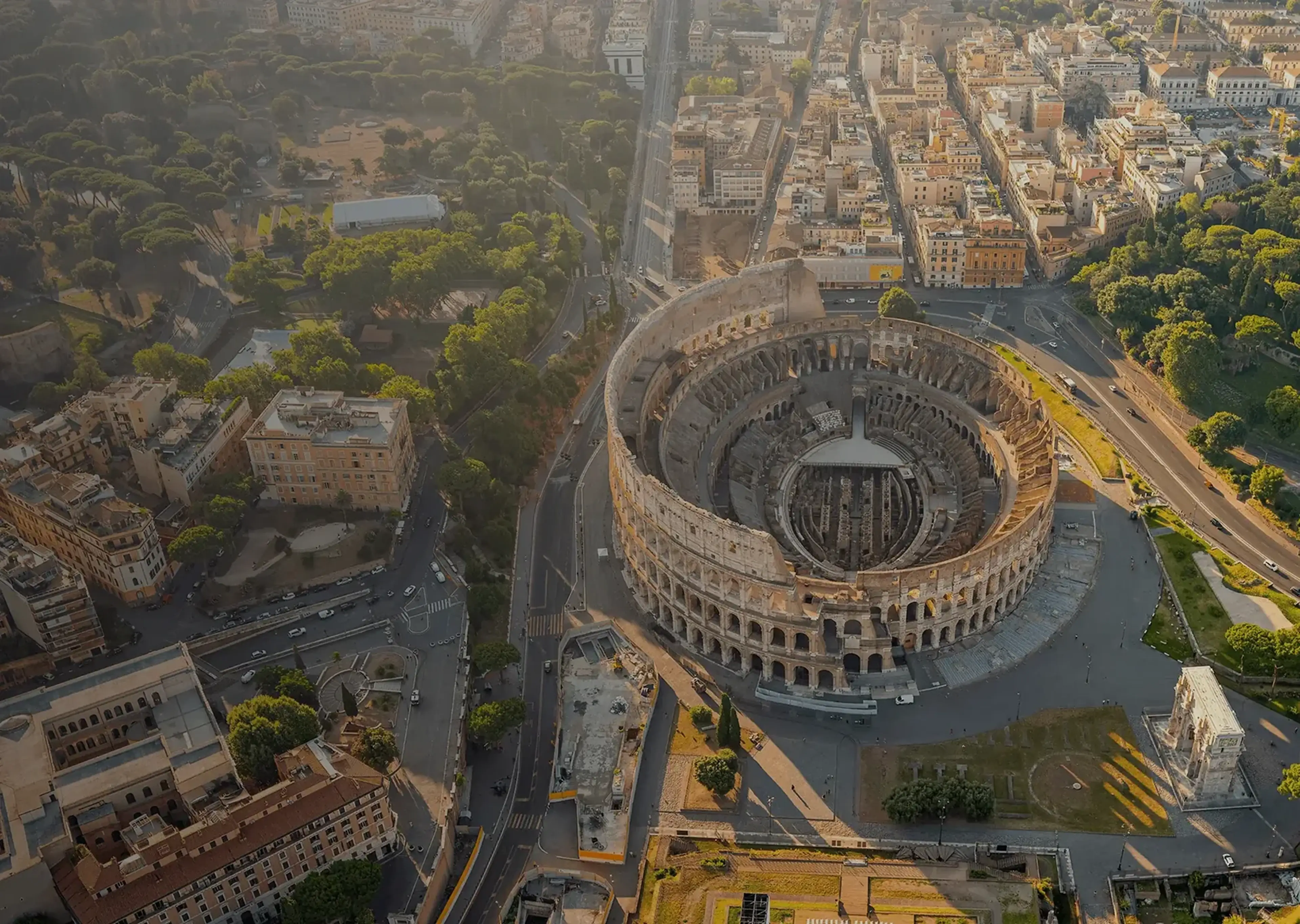 Aerial view of the Colosseum in Rome surrounded by the surrounding cityscape at sunrise