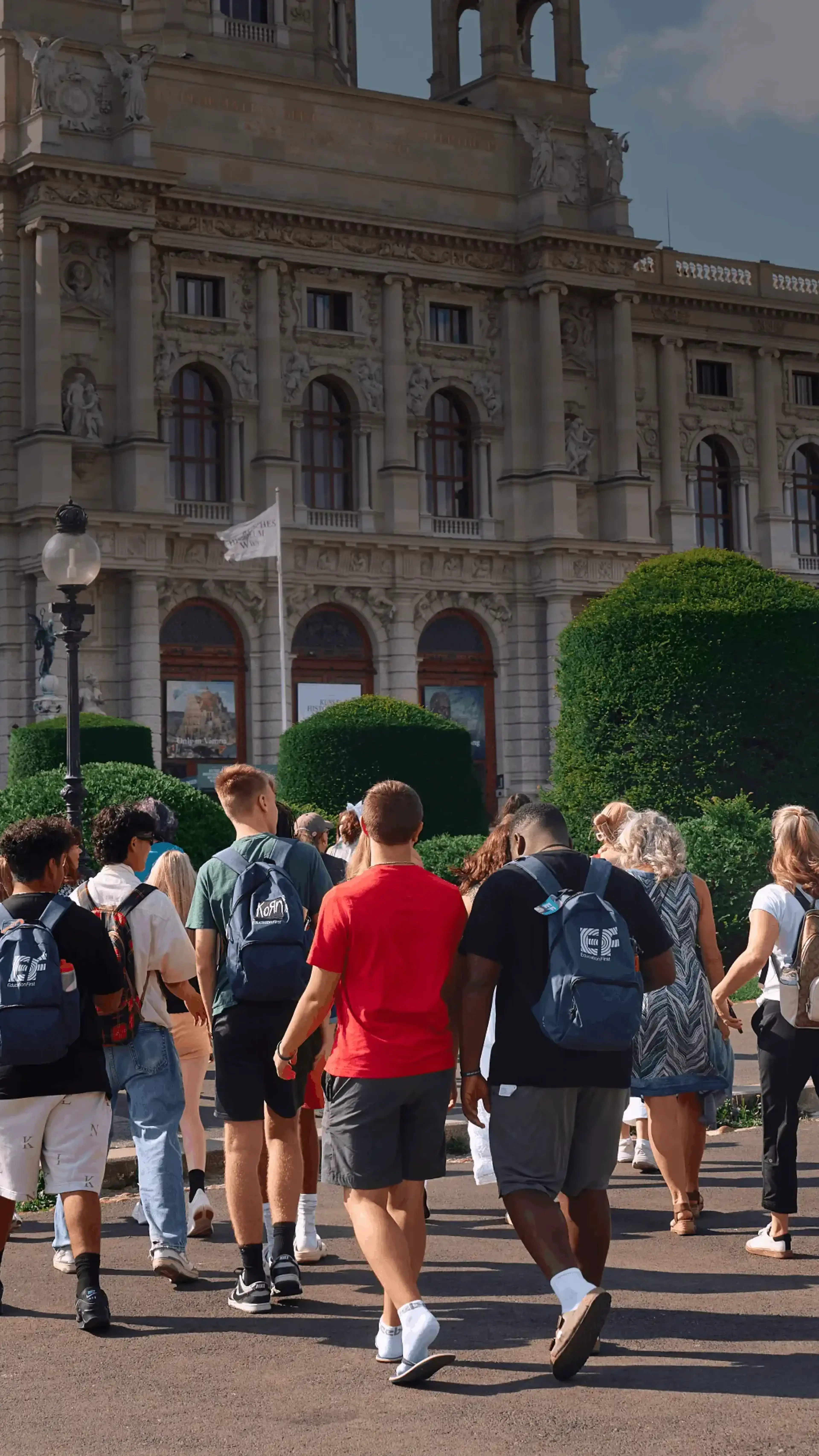 students walking with group leader in front of scenic building in europe