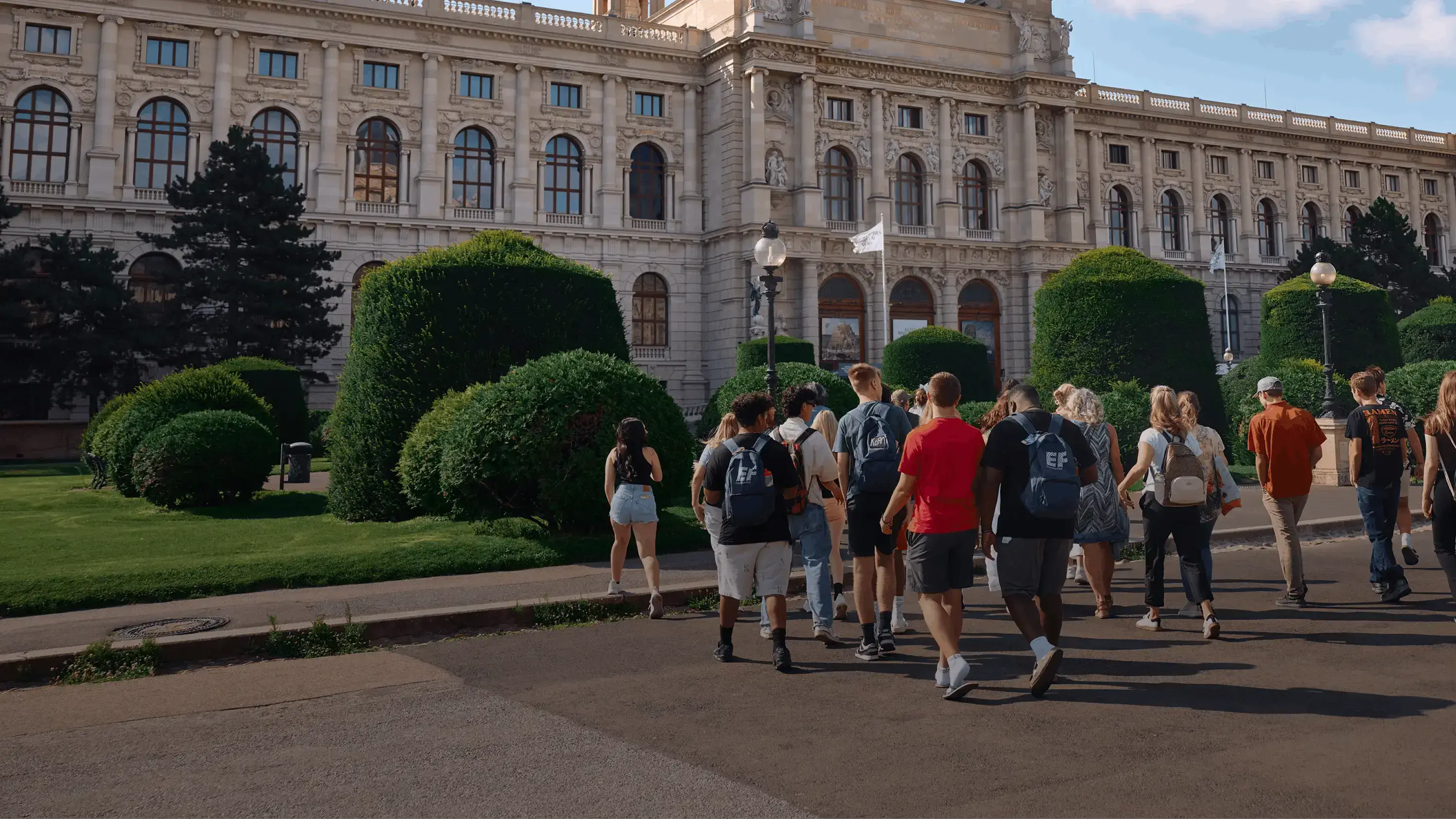 students walking with group leader in front of scenic building in europe