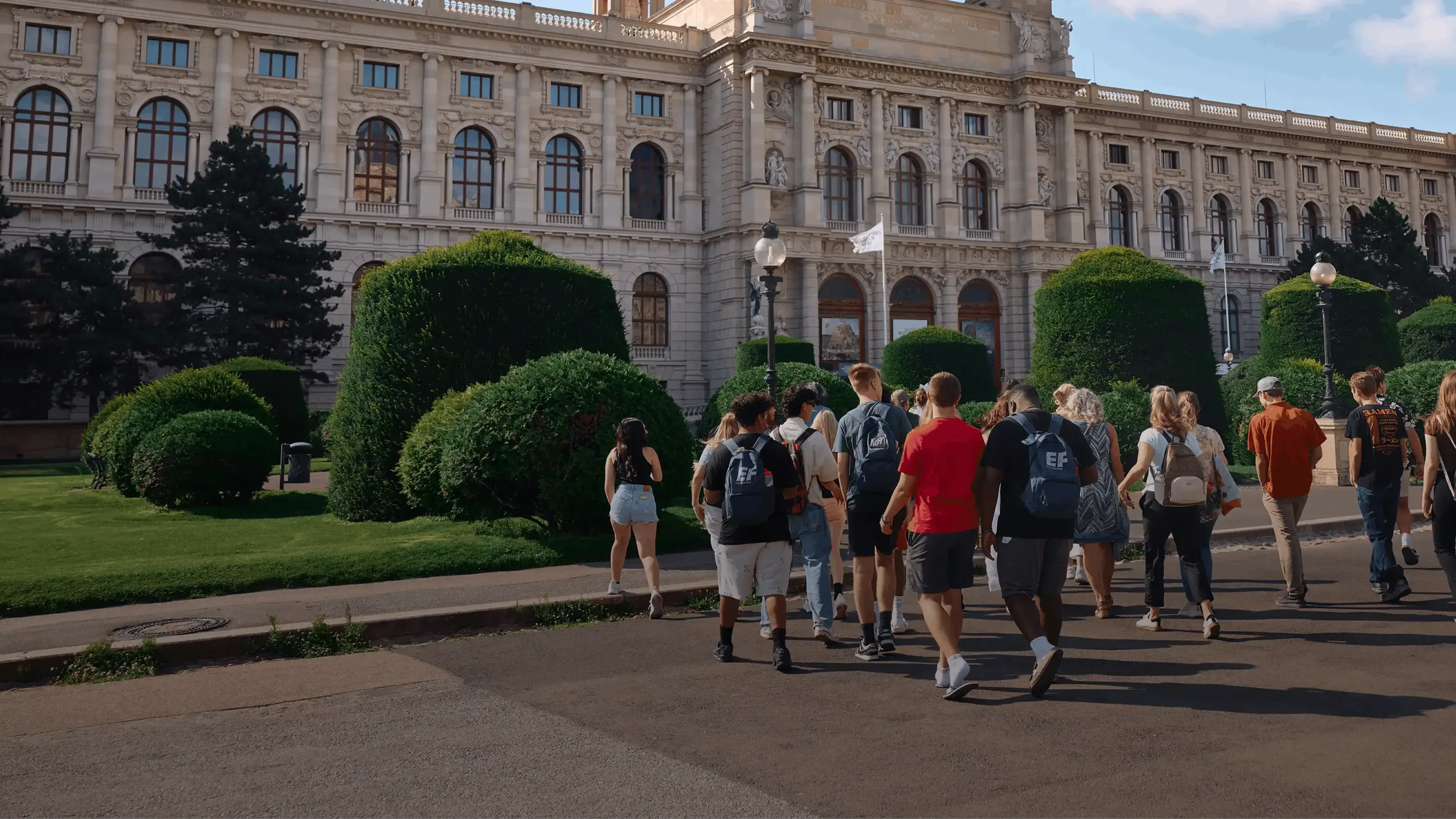 students walking with group leader in front of scenic building in europe