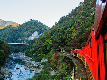 red train winding around a mountain in japan