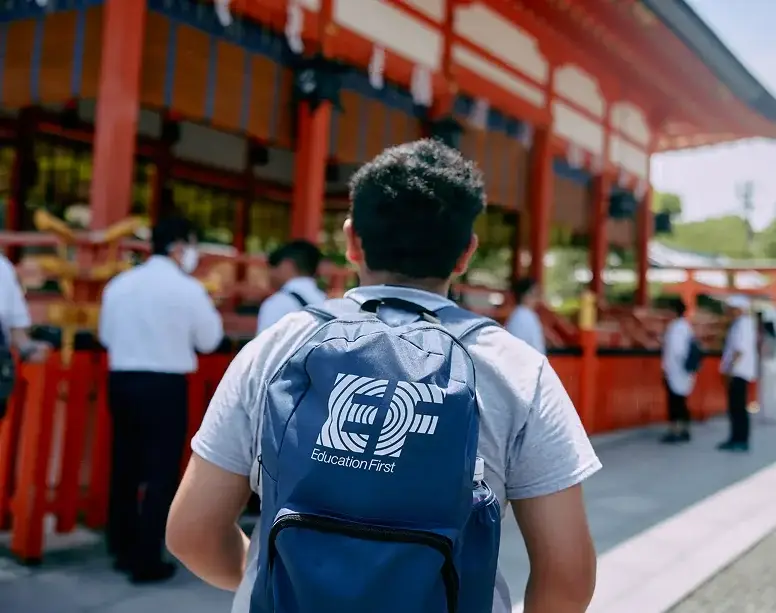 Traveler wearing an EF Education First backpack outside traditional red architecture in Japan