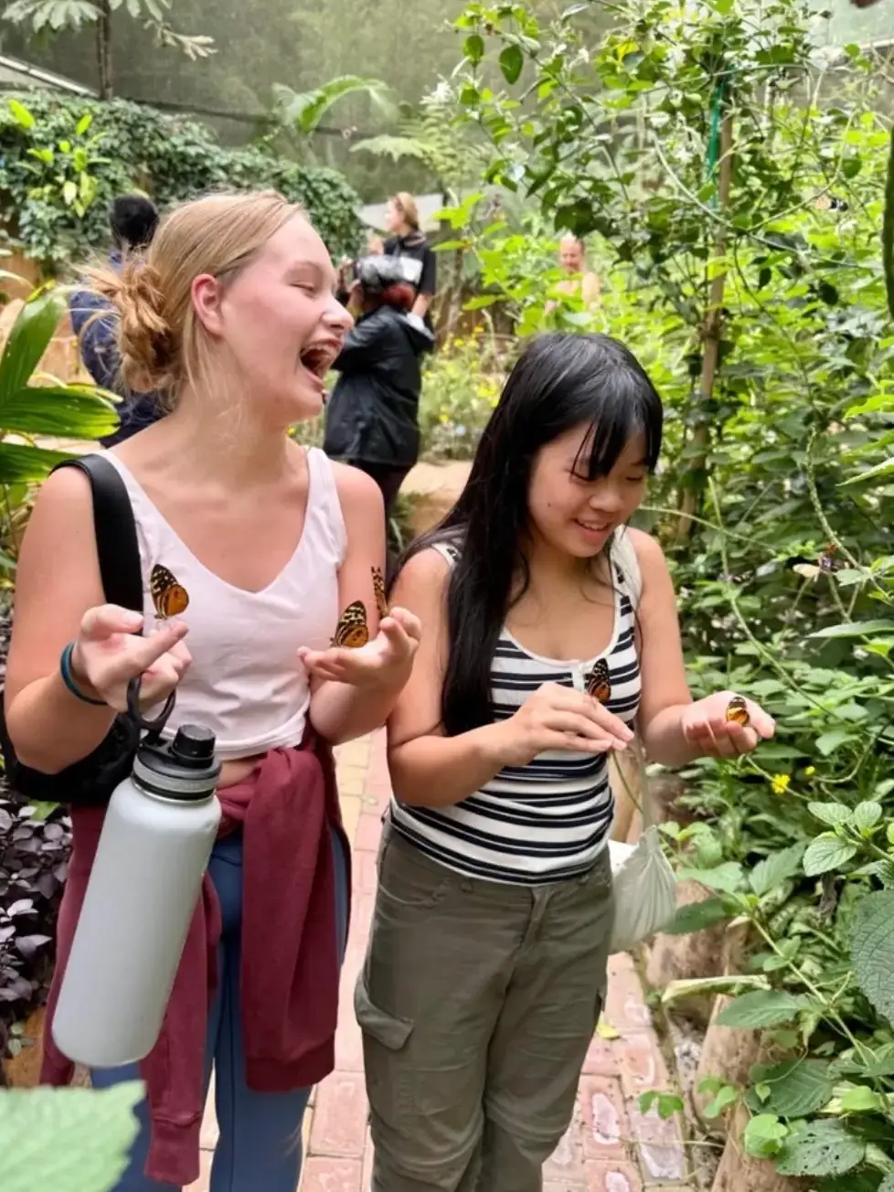 Two travelers holding butterflies on tour
