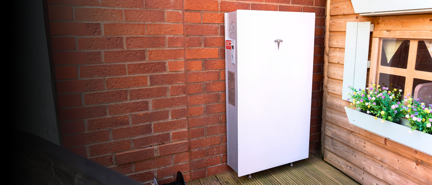 White outdoor unit installed on a wooden deck against a brick wall, near a window with a flower box.