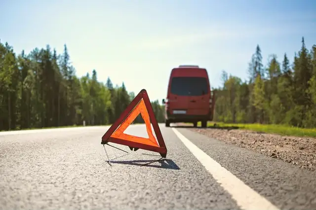Ein Minibus steht am Straßenrand mit Warndreieck.