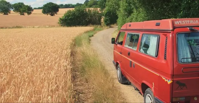 Älterer roter Van auf einem Feldweg.