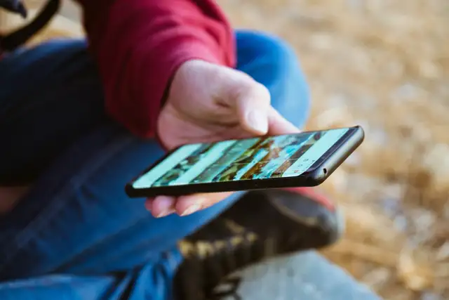 Person hat ein Handy in der Hand und schaut sich Naturplätze an