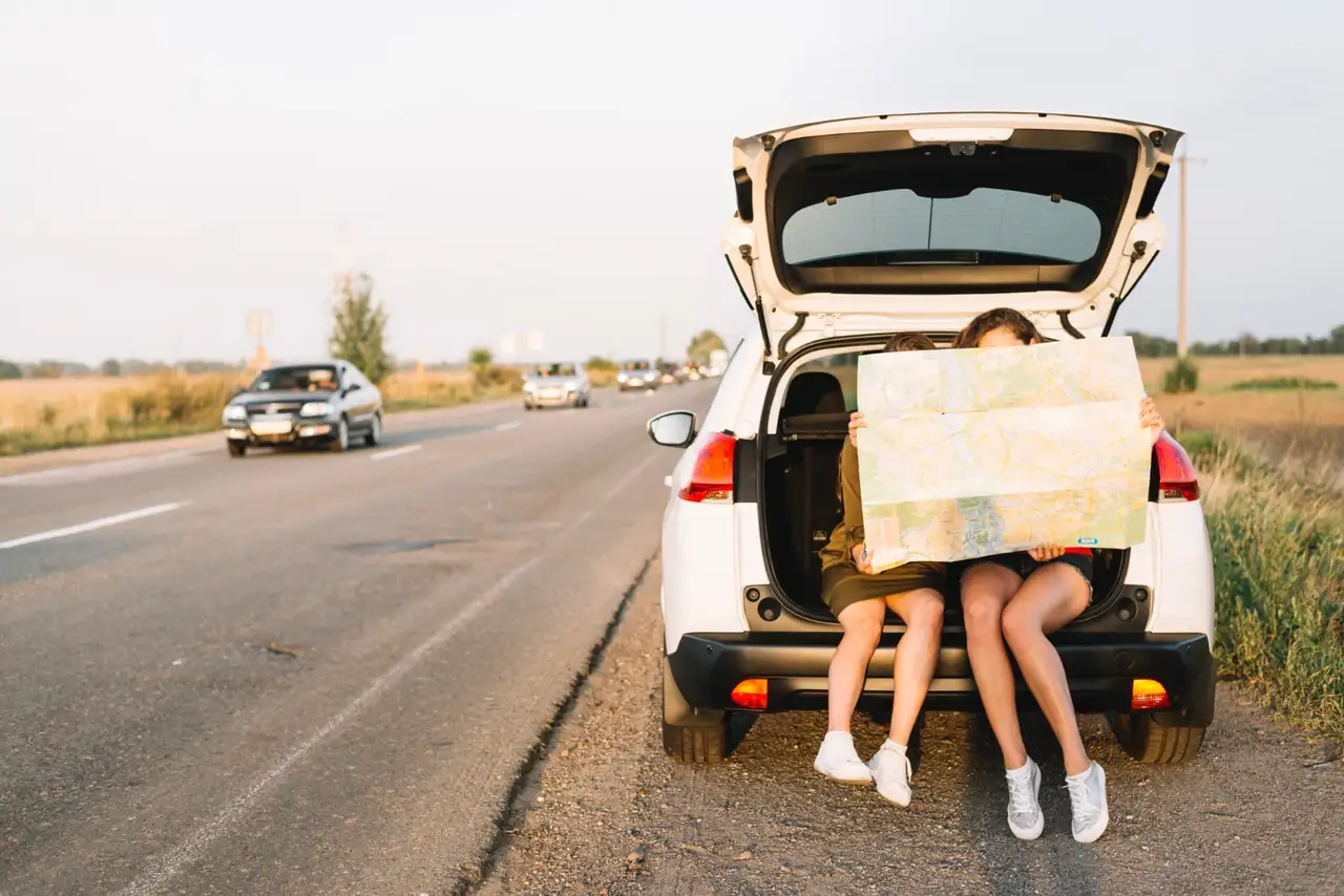 Zwei Personen sitzen hinten im Kofferraum eines Autos und schauen auf eine Karte