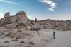 Frau geht in trockener Landschaft zu ihrem Camper