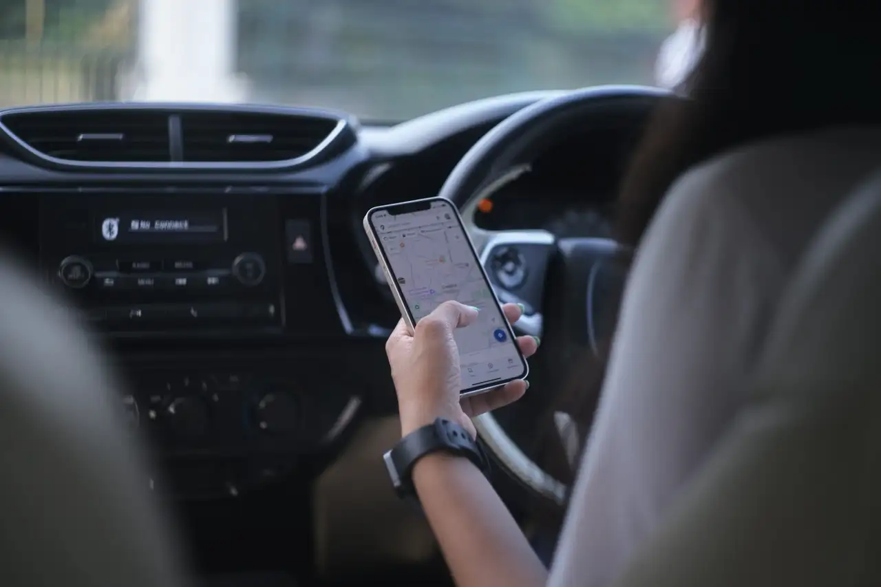 Person schaut auf Google Maps auf dem Handy im Auto
