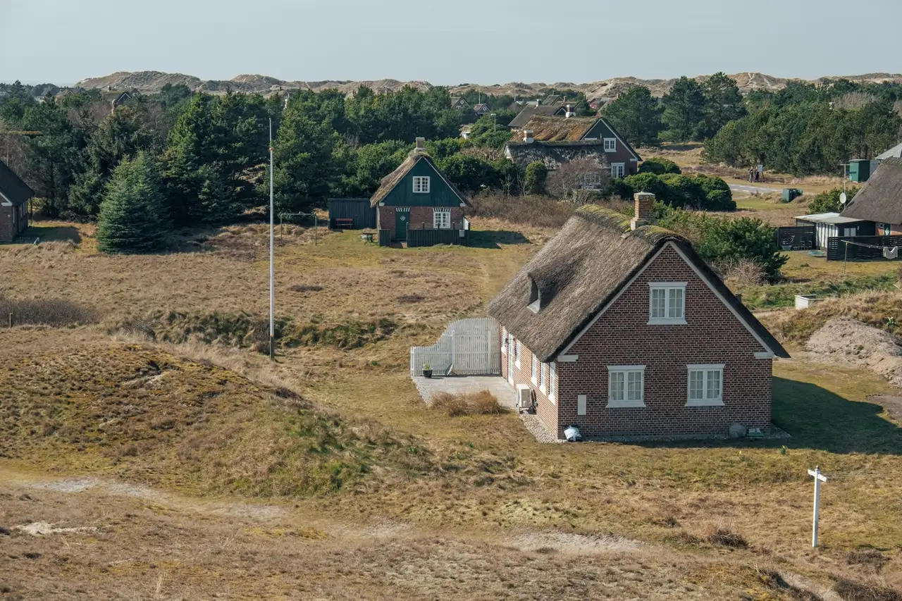 Mehrere Hütten stehen vor einer Dünenlandschaft