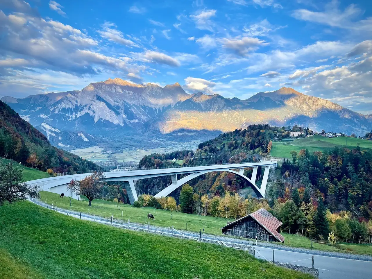 Eine Brücke, die in der Schweiz vor Bergen im Hintergrund lang führt
